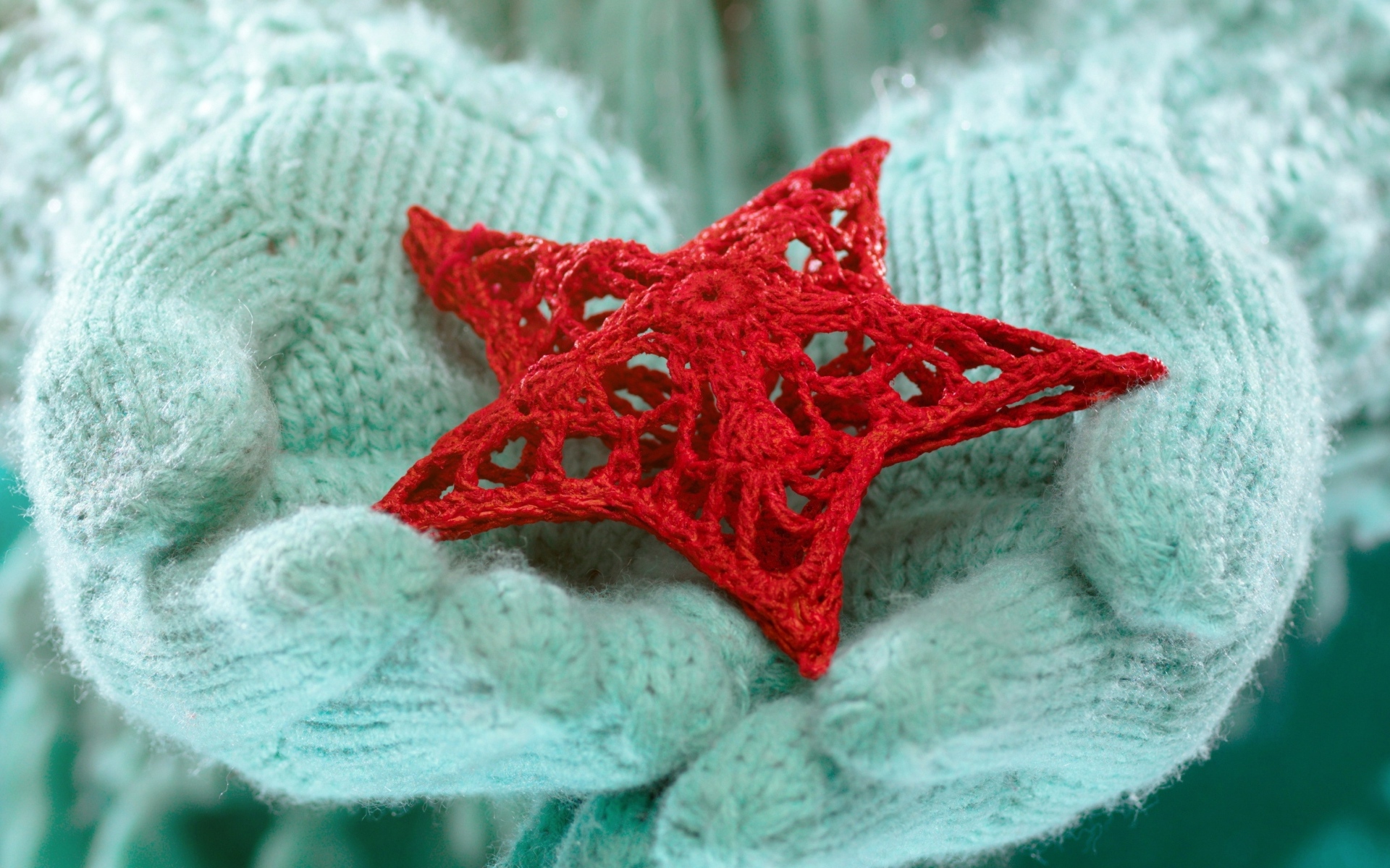 Красная вязаная звезда в руках в варежках