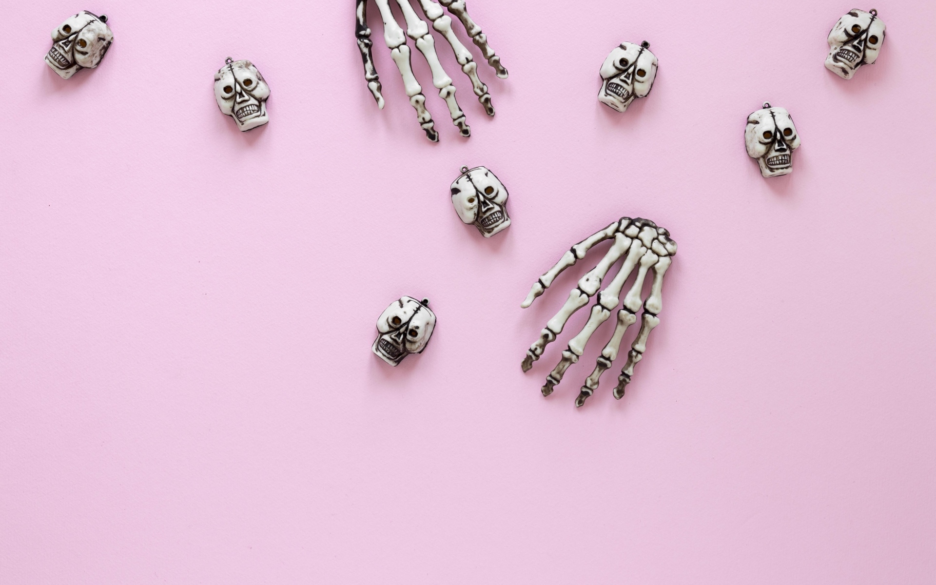 Кисти рук скелета и черепа на розовом фоне