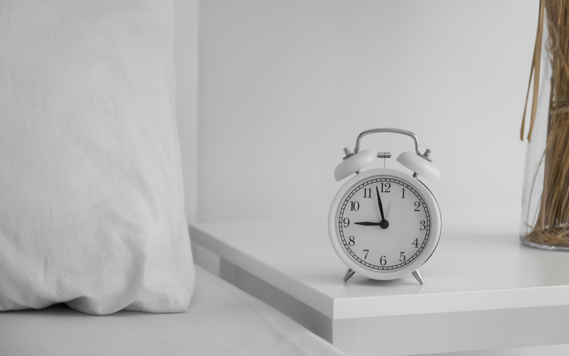 Будильник стоит на тумбочке у кровати 