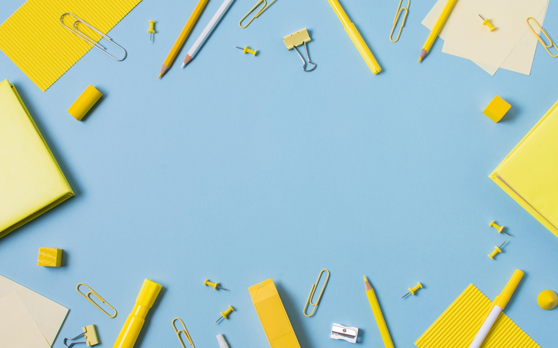 Желтые канцелярские предметы на голубом столе