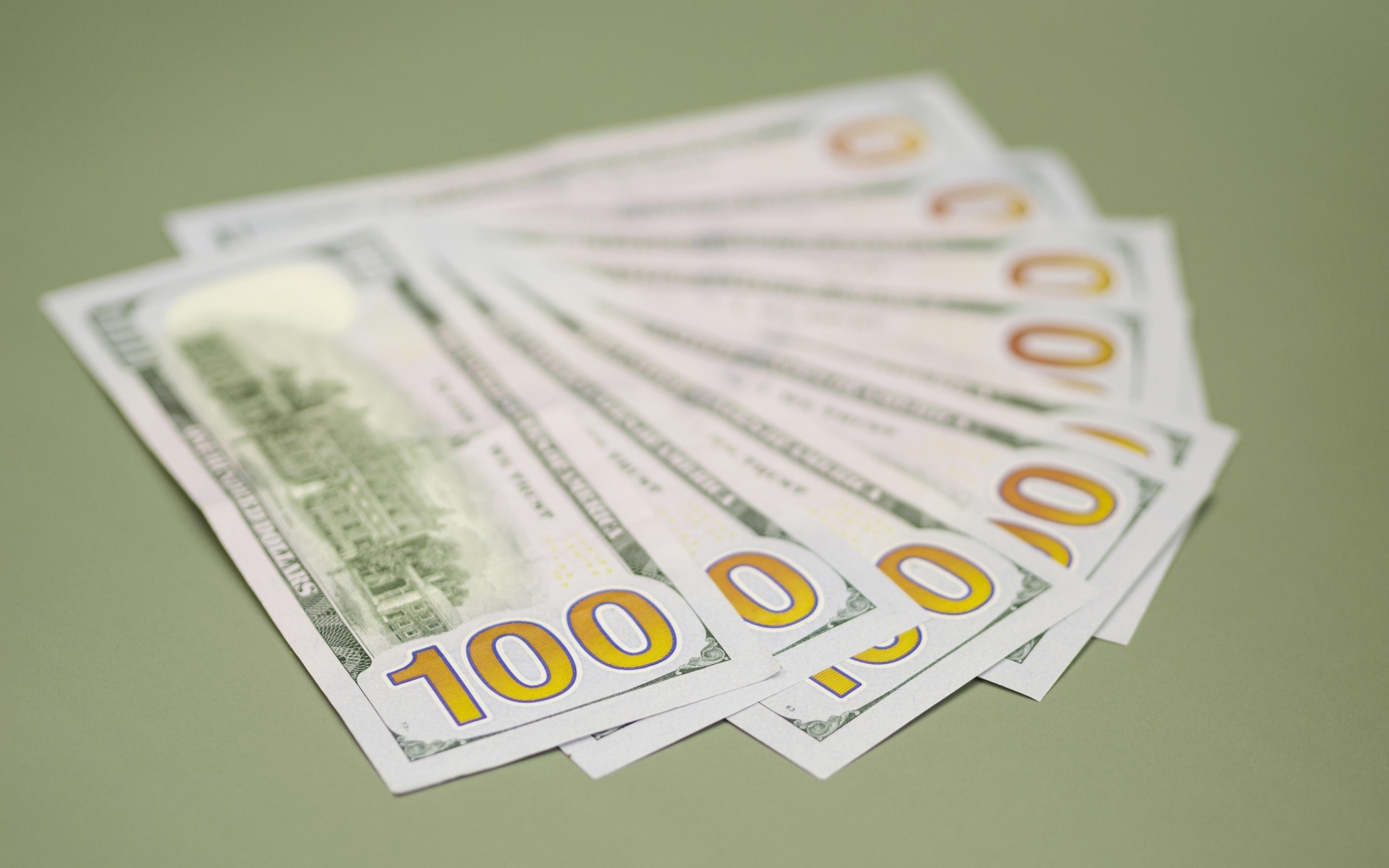 Пачка стодолларовых купюр на зеленом фоне