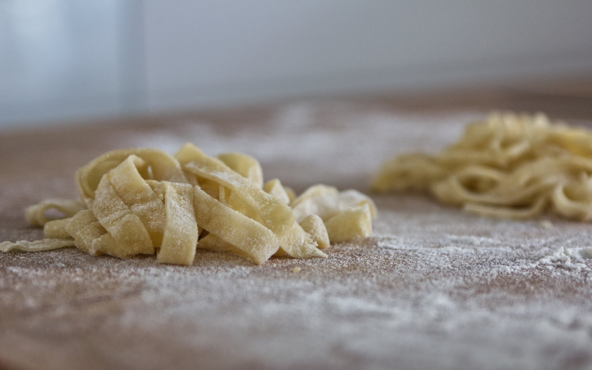 Сырое тесто для лапши на покрытом мукой столе