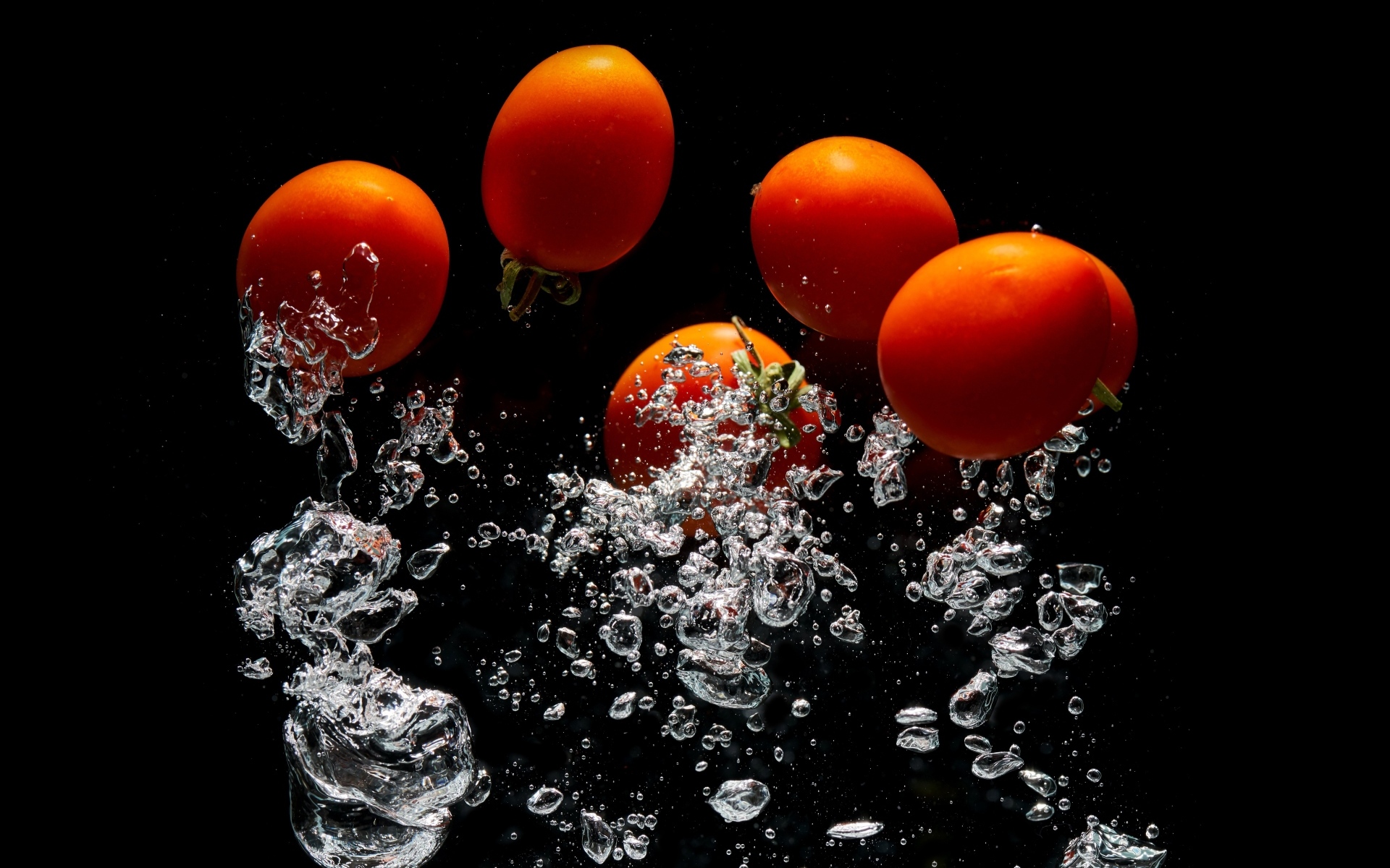 Красные помидоры в воде на черном фоне