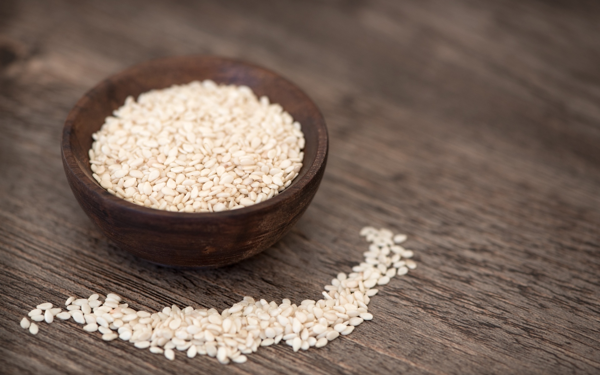 Зерна кунжута в деревянной миске на столе