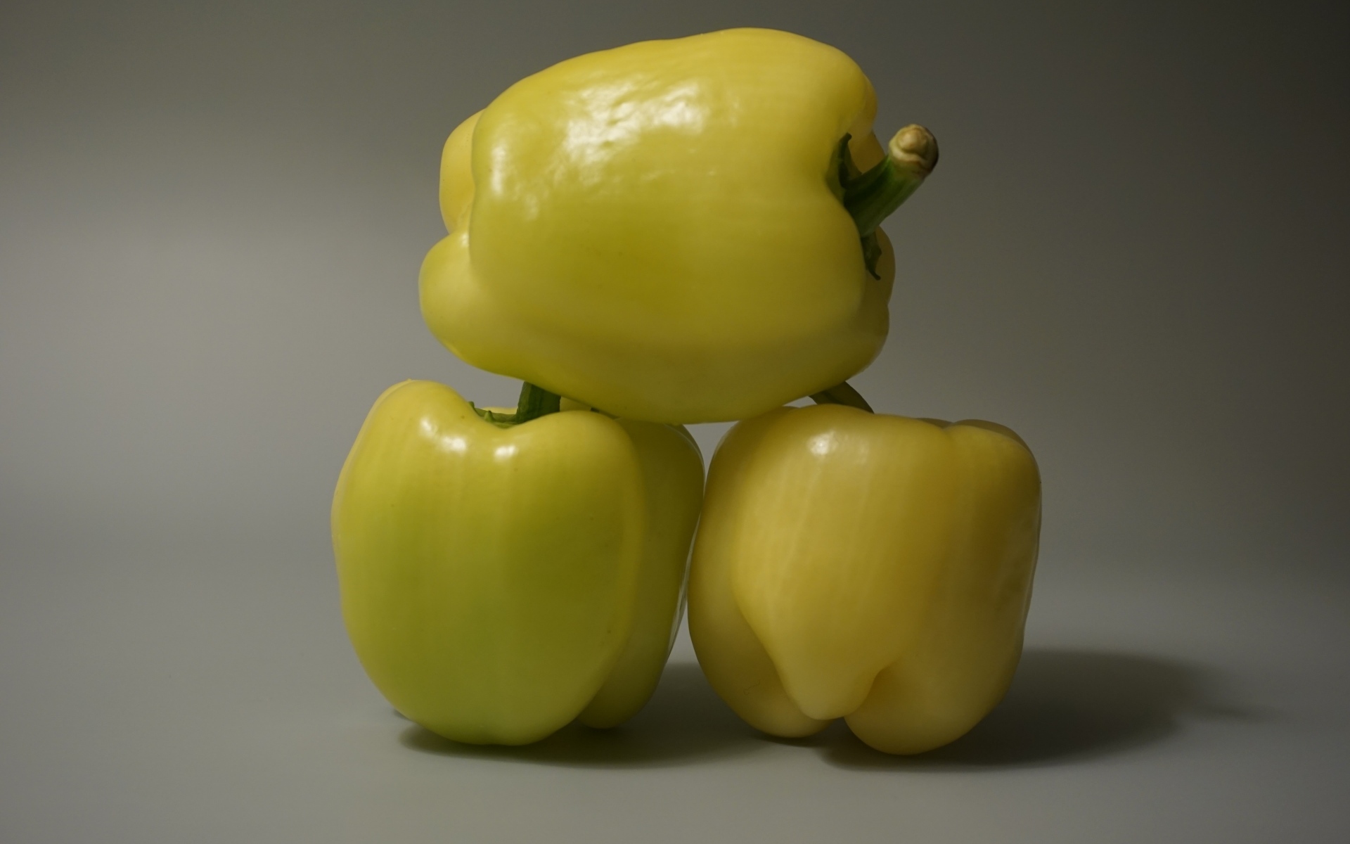Три желтых перца на сером фоне