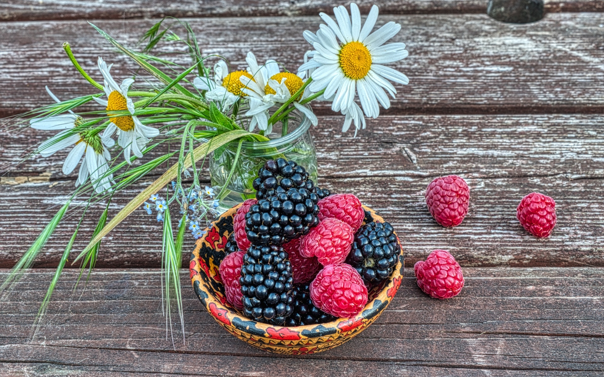 Ягоды черники и малины на столе с ромашками