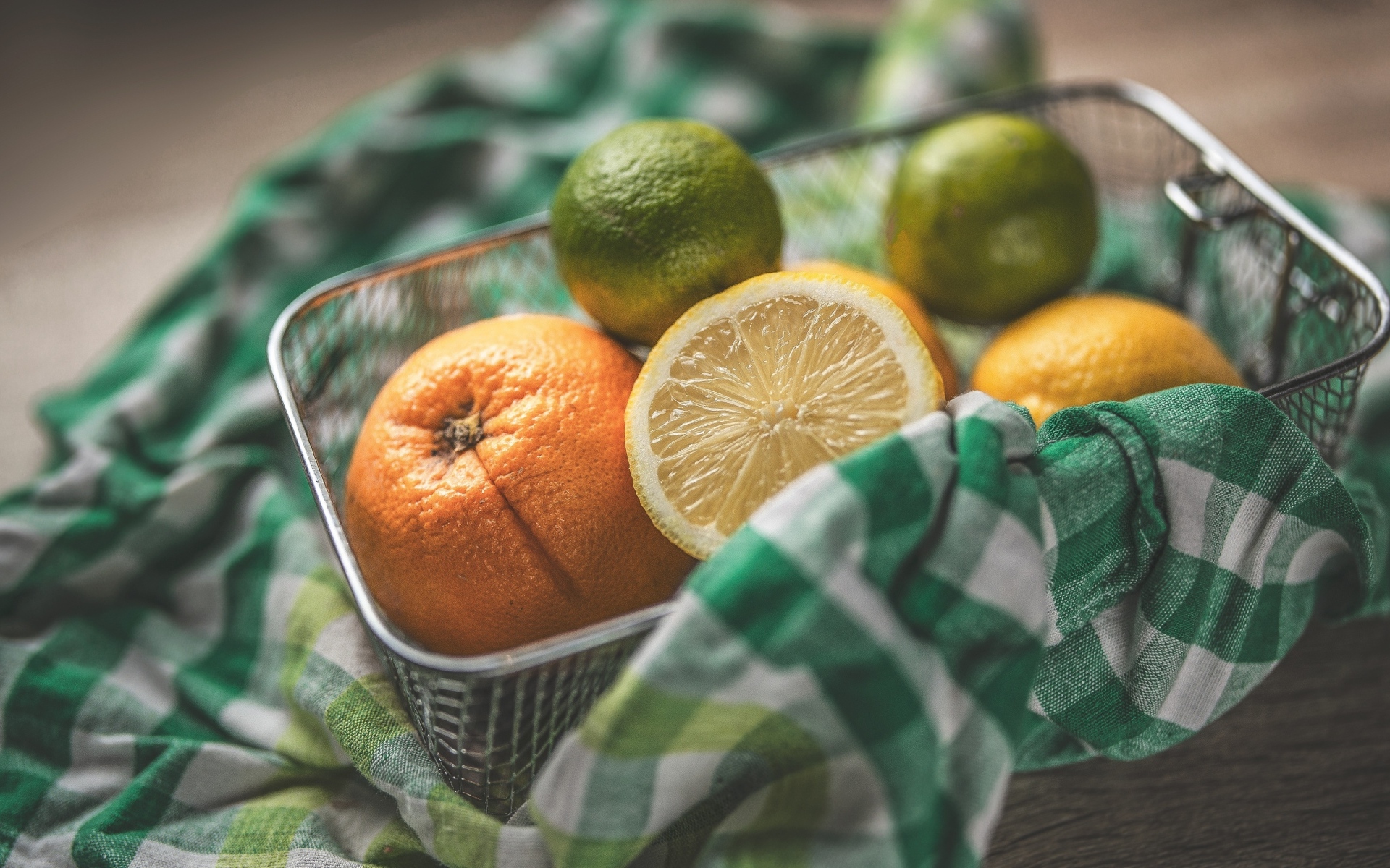 Цитрусовые фрукты в железной корзинке на столе
