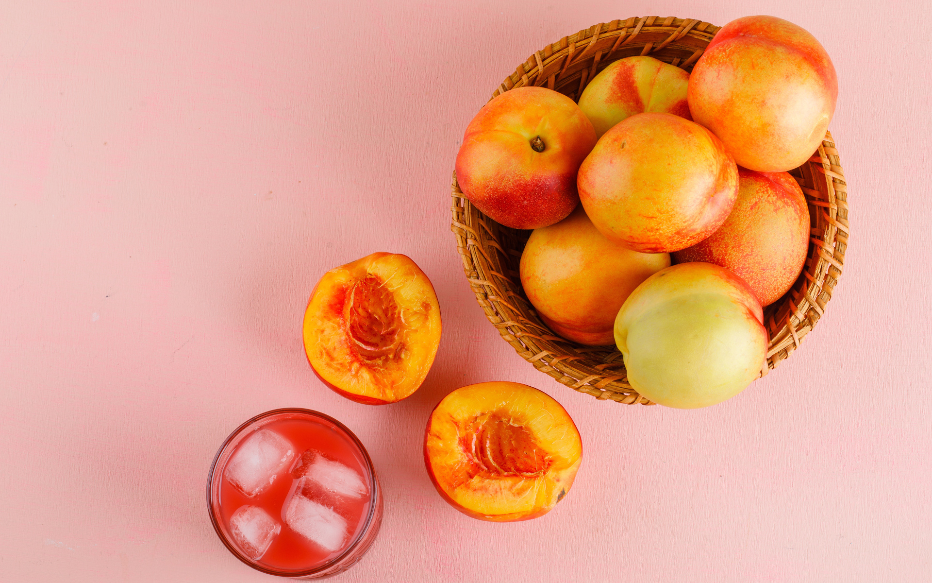 Свежий нектарин в корзине на розовом столе