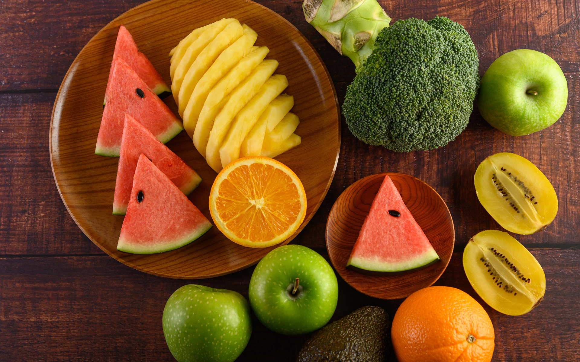 Фрукты и брокколи на столе с доской