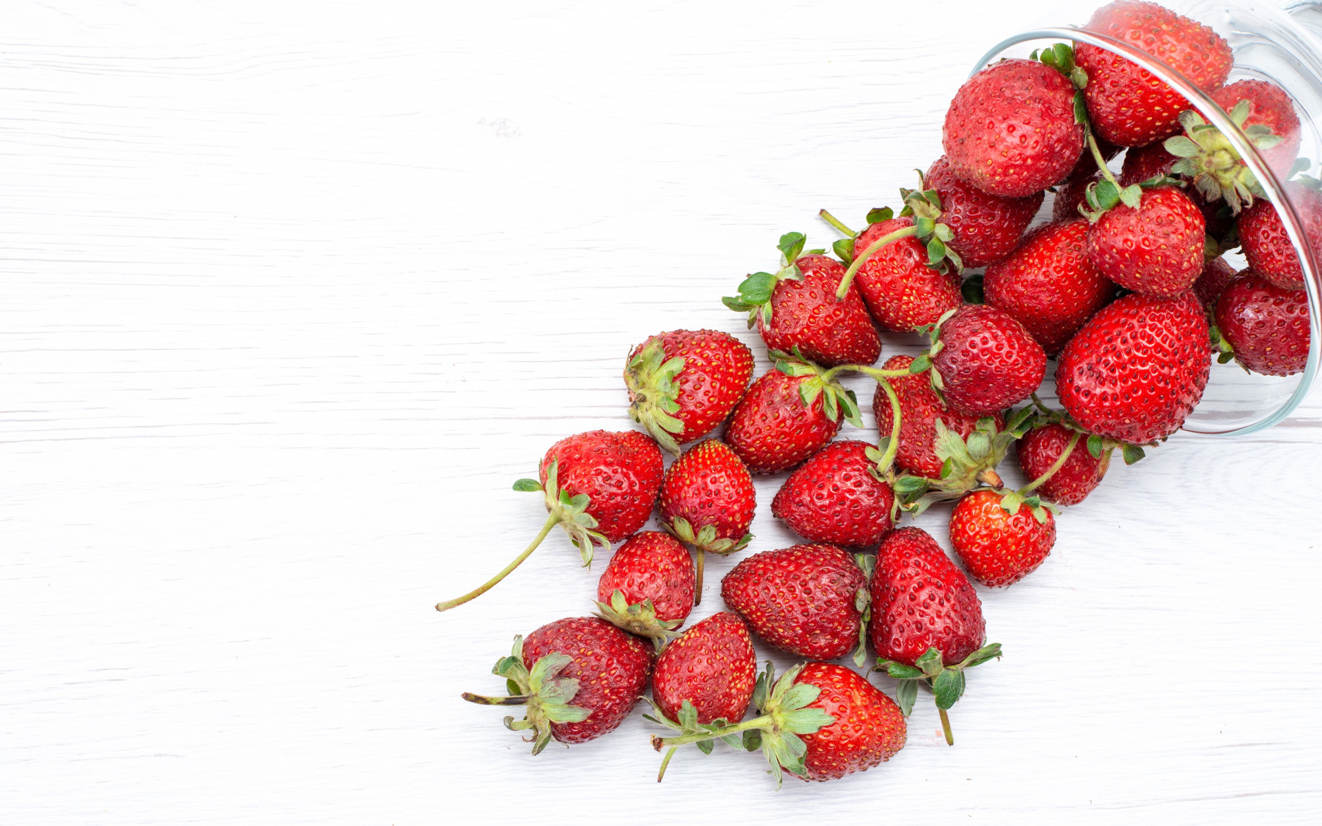 Стеклянный стакан с ягодами клубники на столе