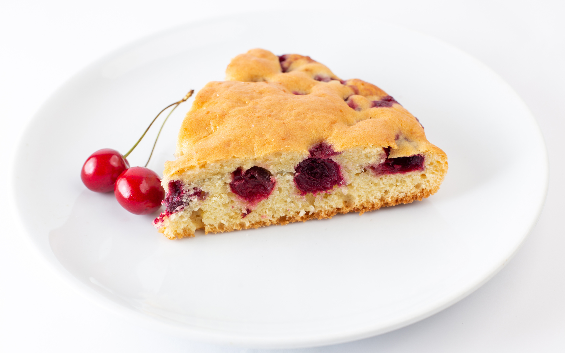 Кусок вишневого пирога с ягодами на тарелке