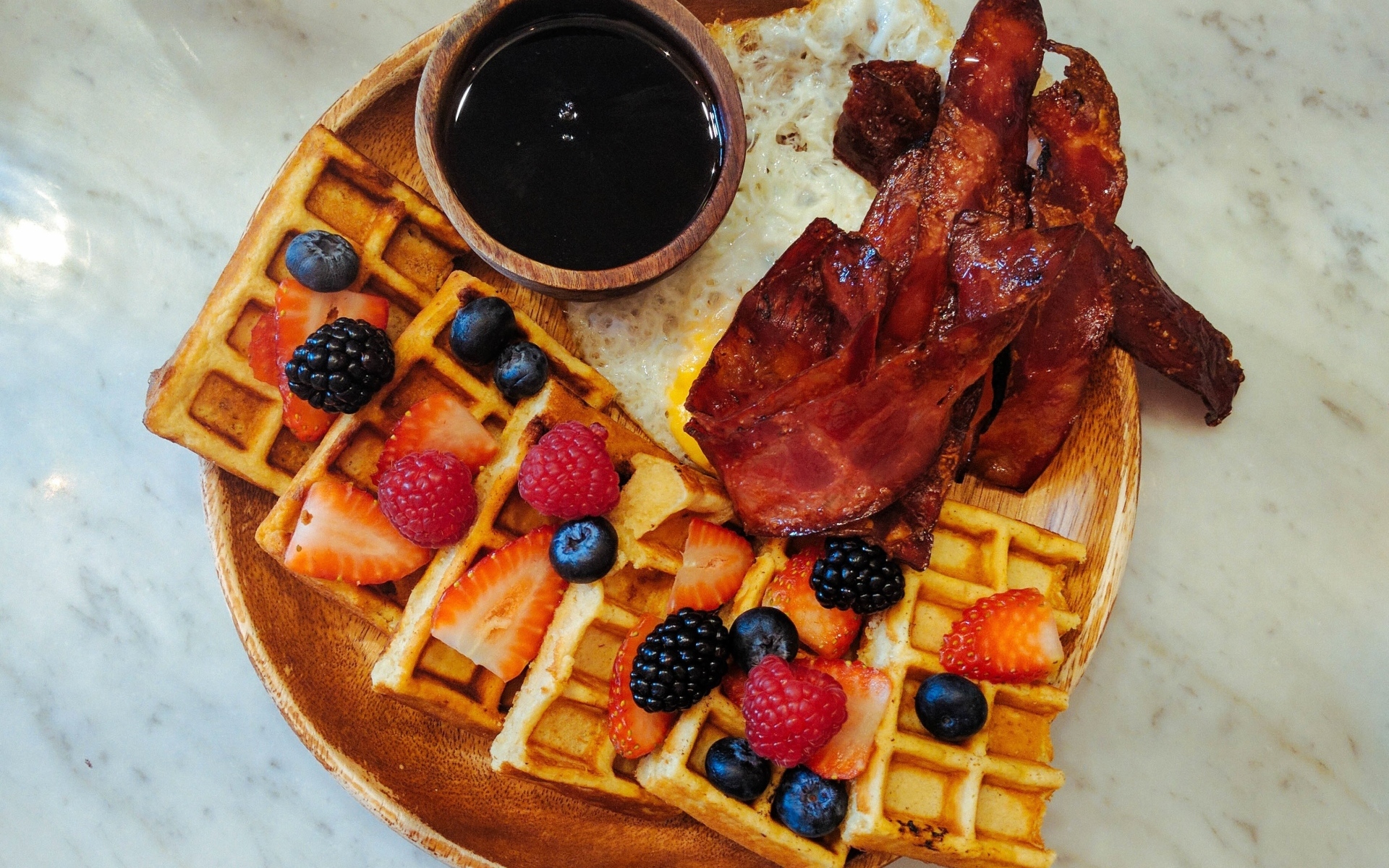 Сладкие вафли с ягодами на тарелке с беконом