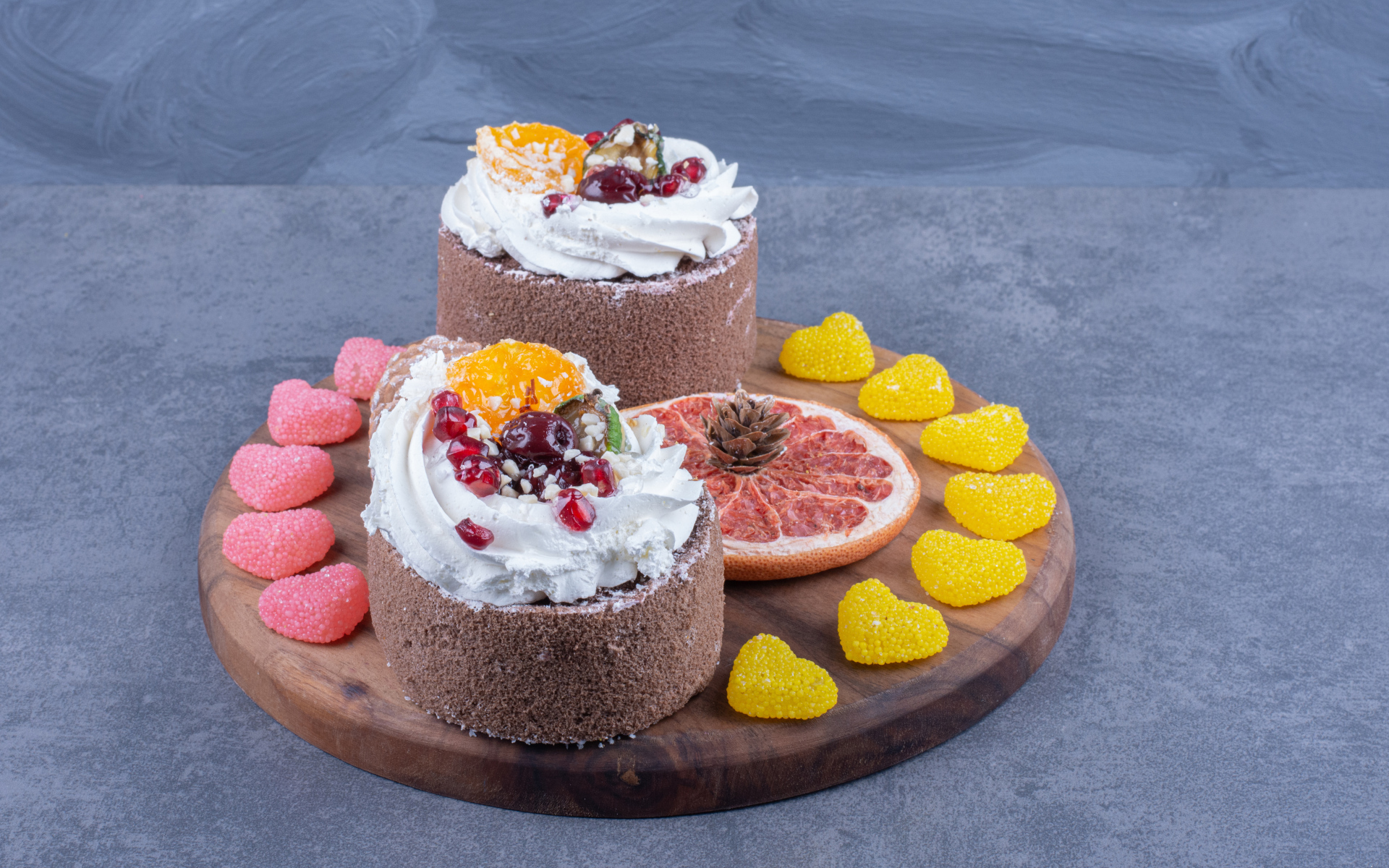 Два пирожных на деревянной доске с мармеладными конфетами