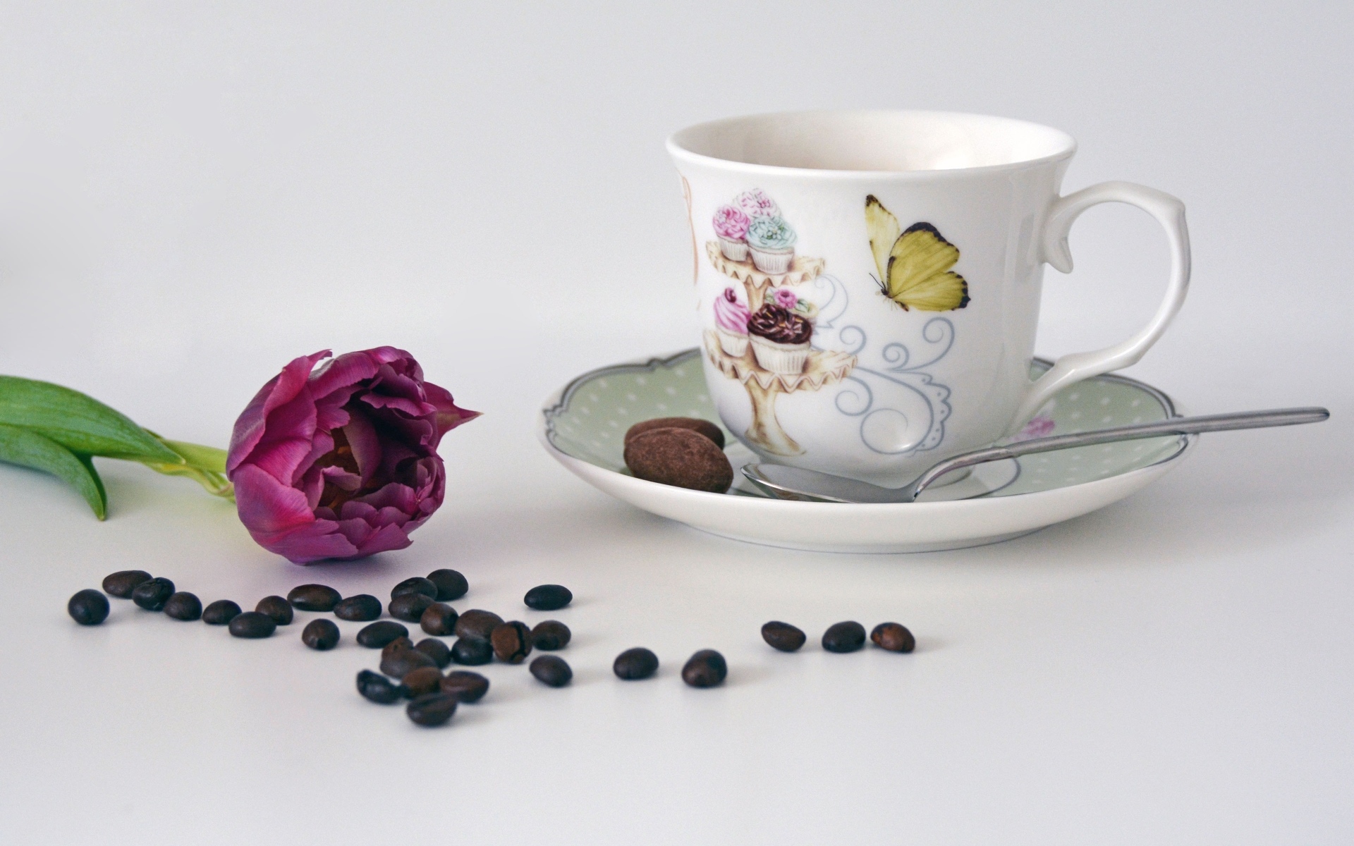 Чашка на столе с кофейными зернами и тюльпаном