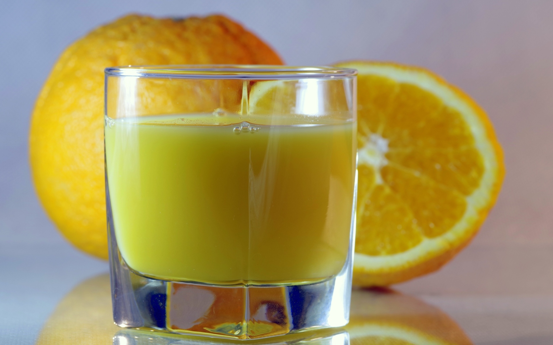 Оранжевый апельсиновый сок в стакане на столе с плодами