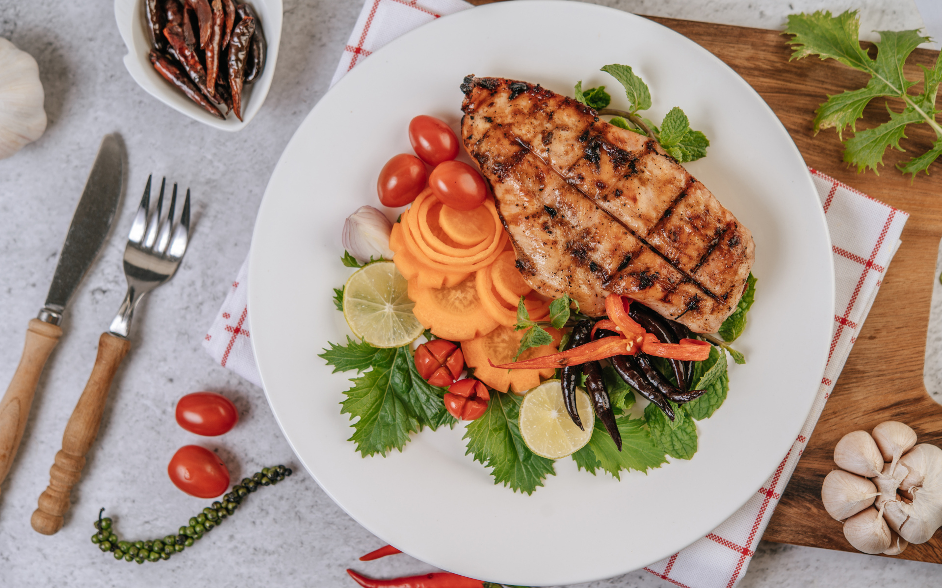 Кусок жареной курицы на большой белой тарелке с овощами