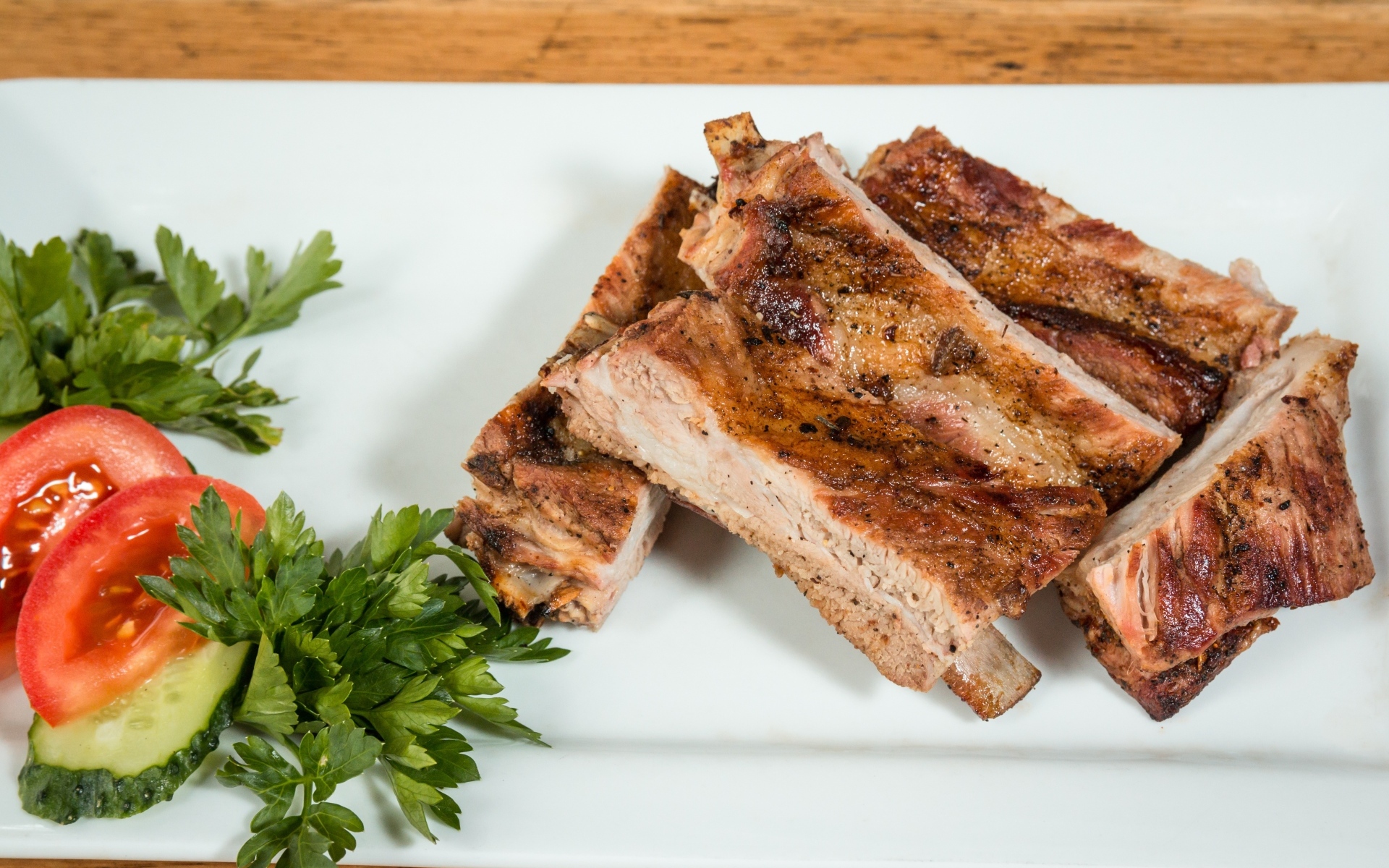 Свиные ребра на тарелке с овощами и зеленью