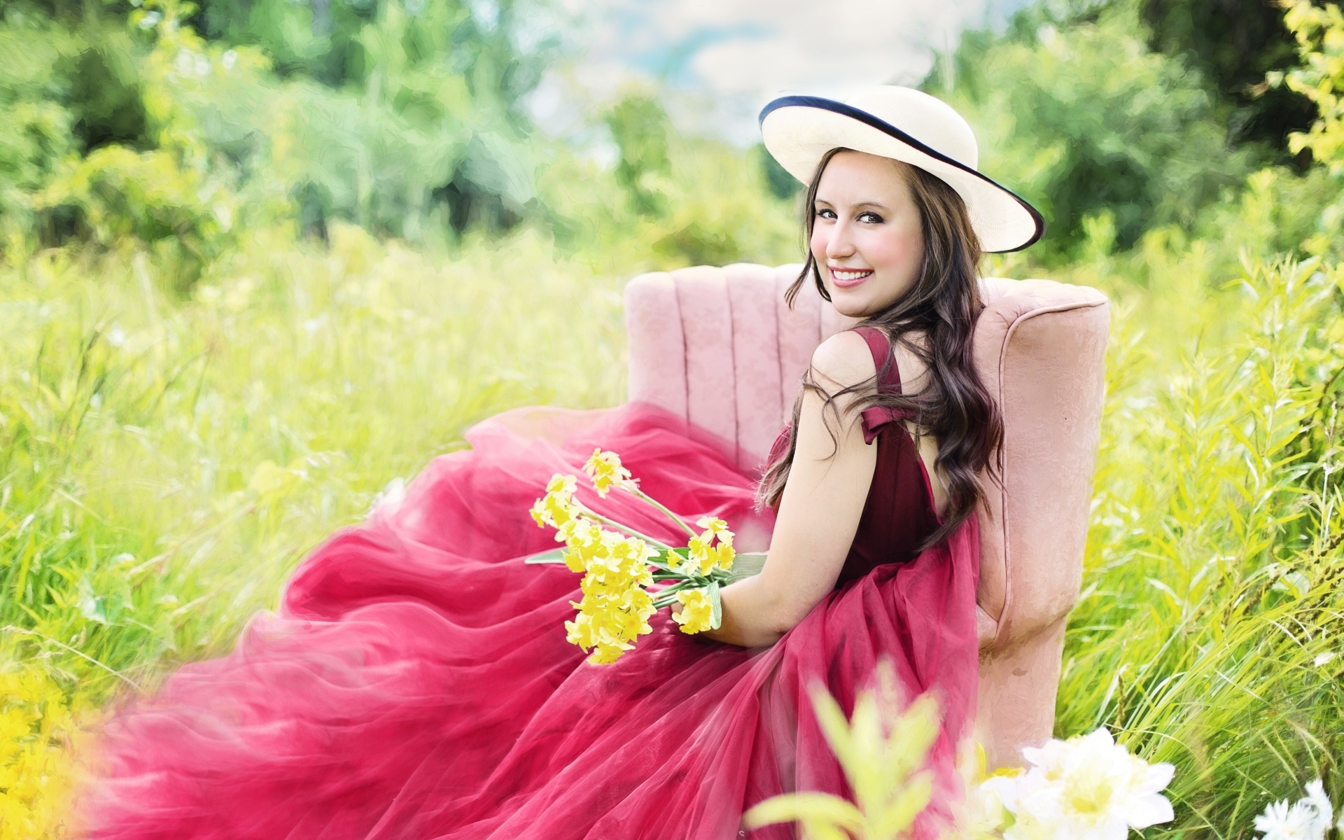 Красивая девушка в розовом платье сидит на кресле в траве