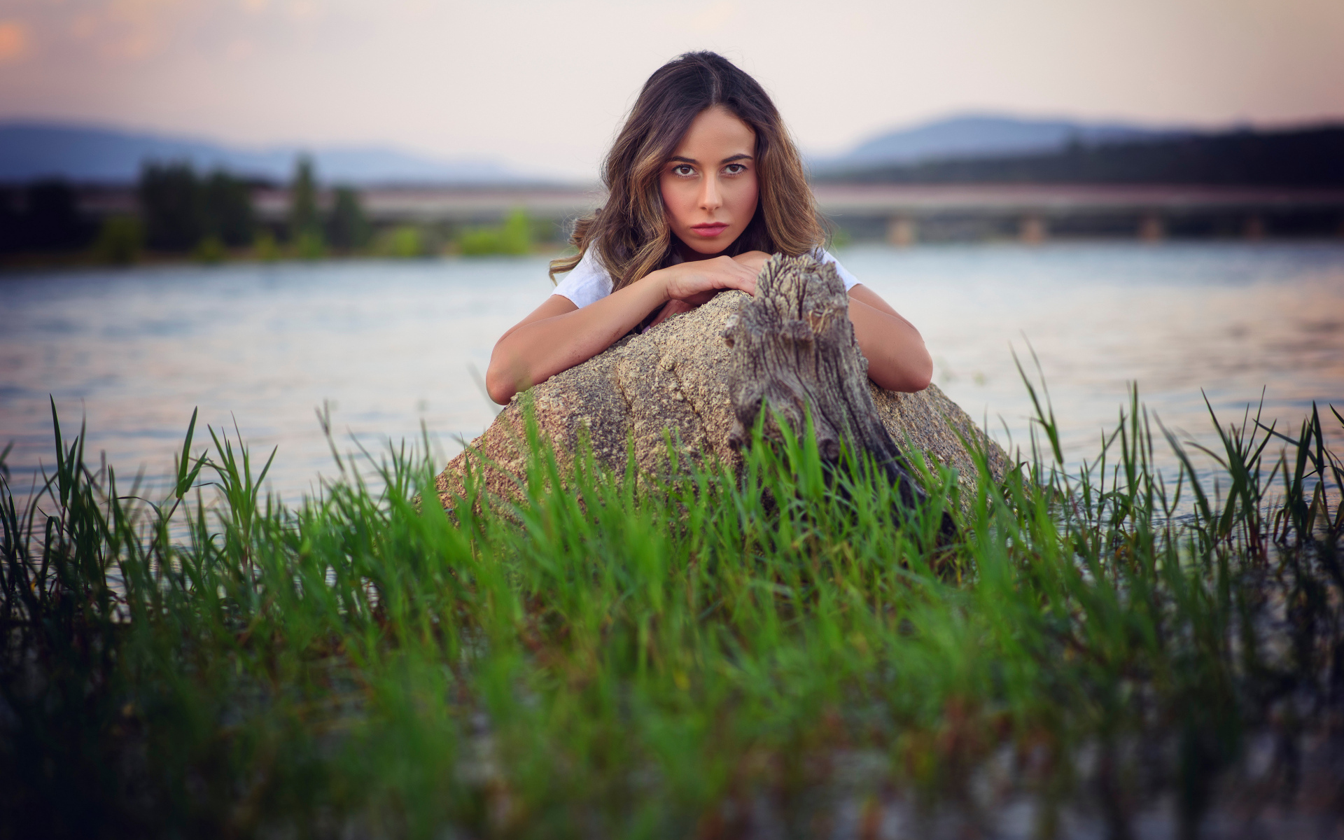 Девушка у воды прячется за камнем