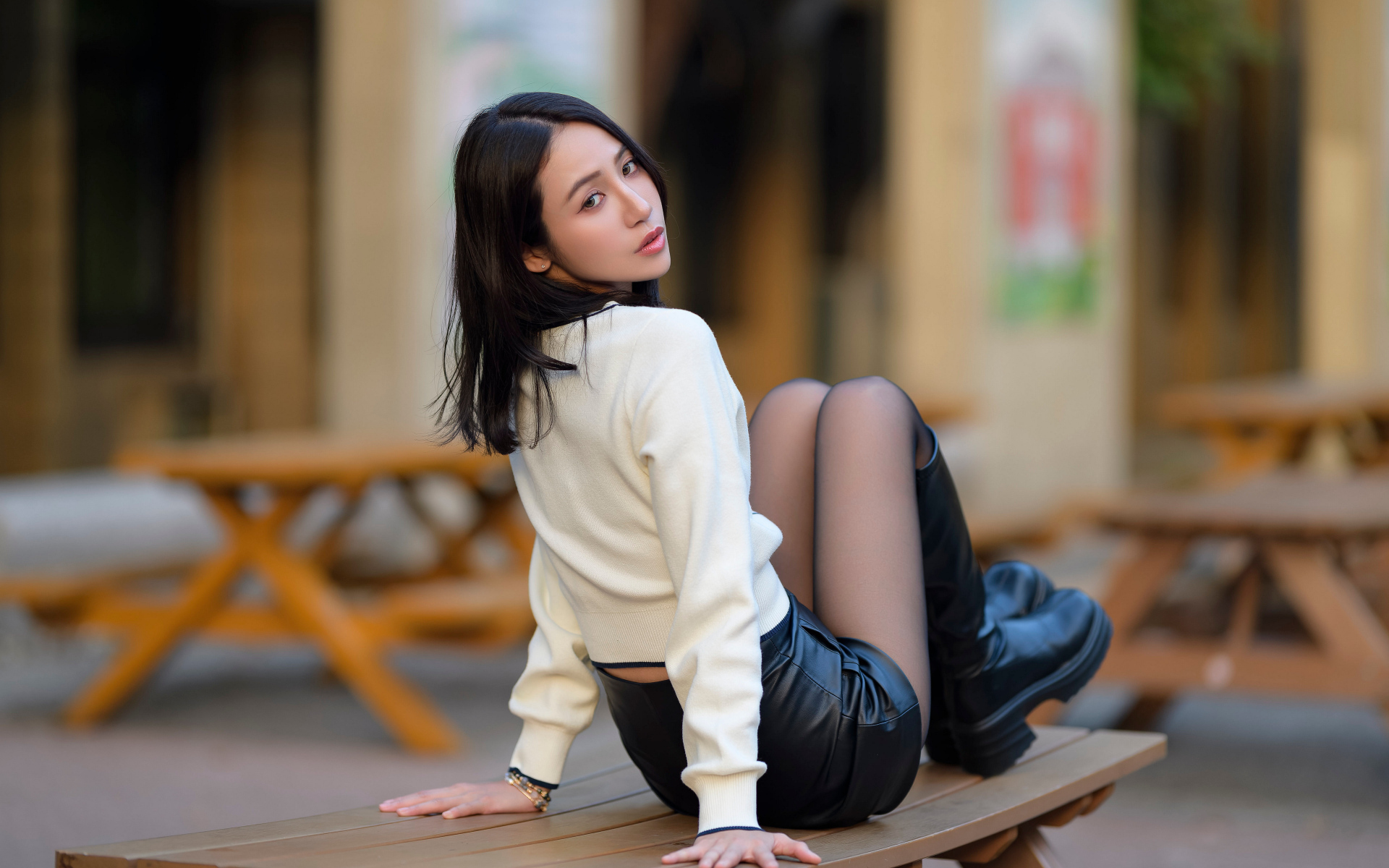 Азиатка в сапогах сидит на столе