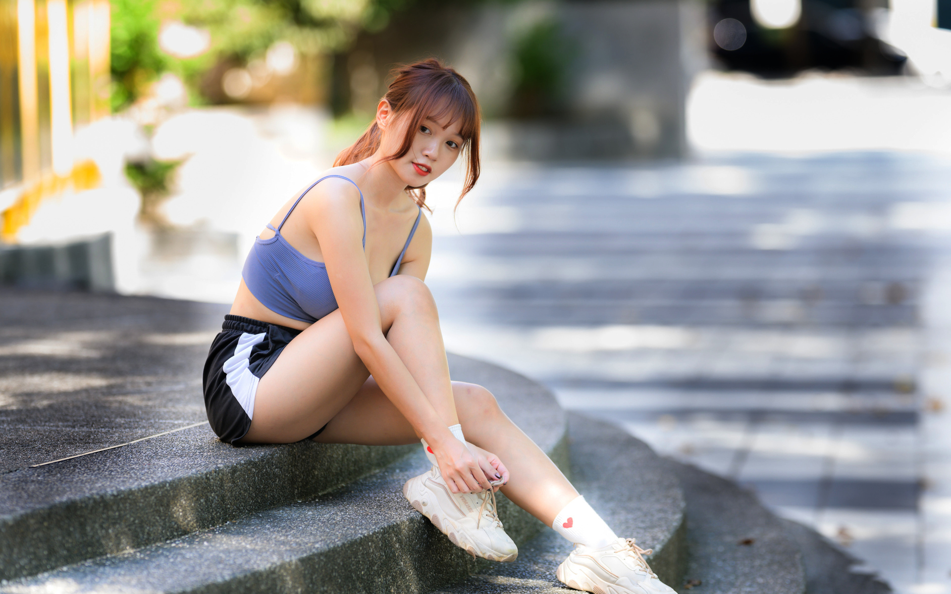 Азиатка в шортах сидит на ступеньках