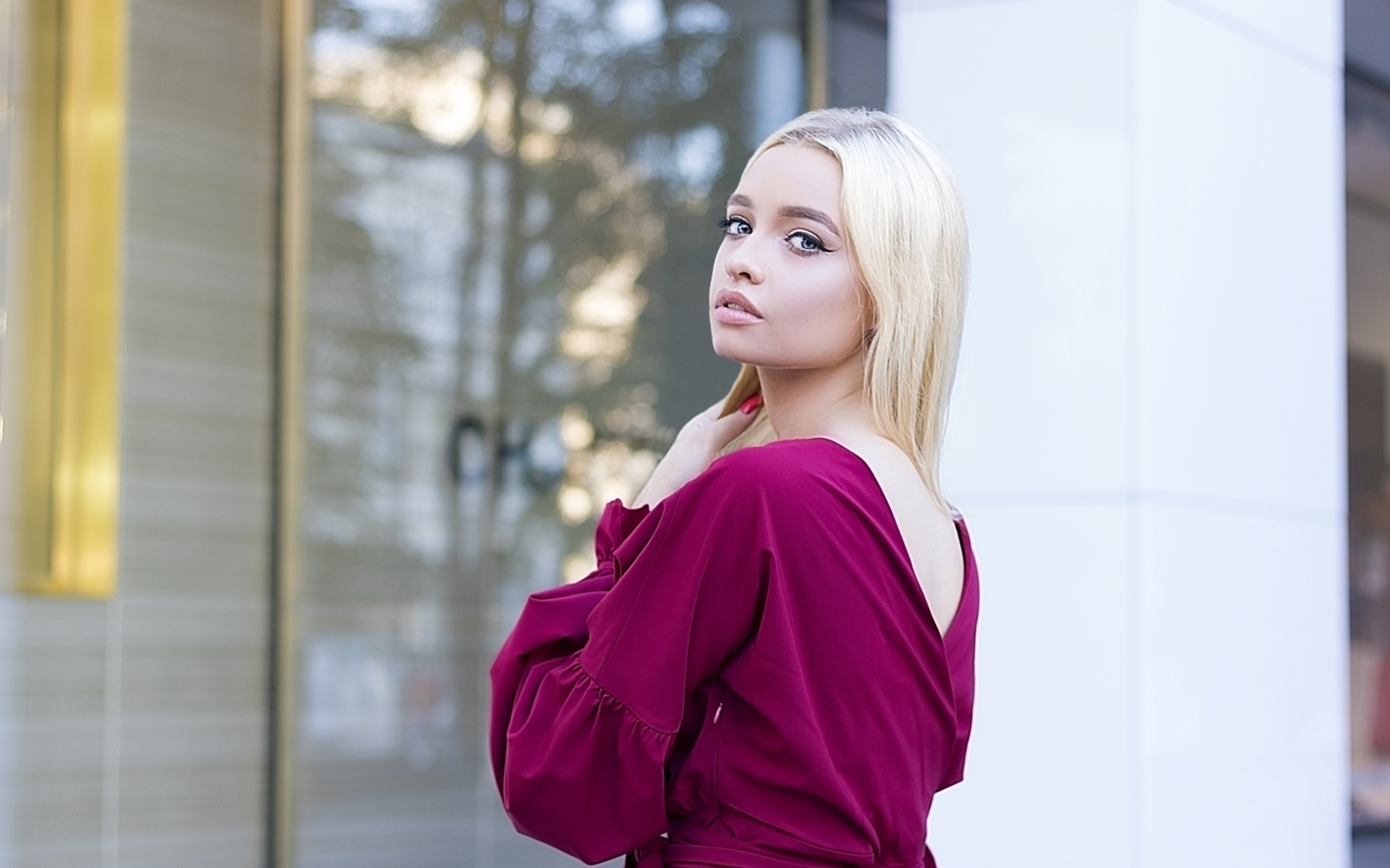 Милая девушка блондинка в платье стоит у здания