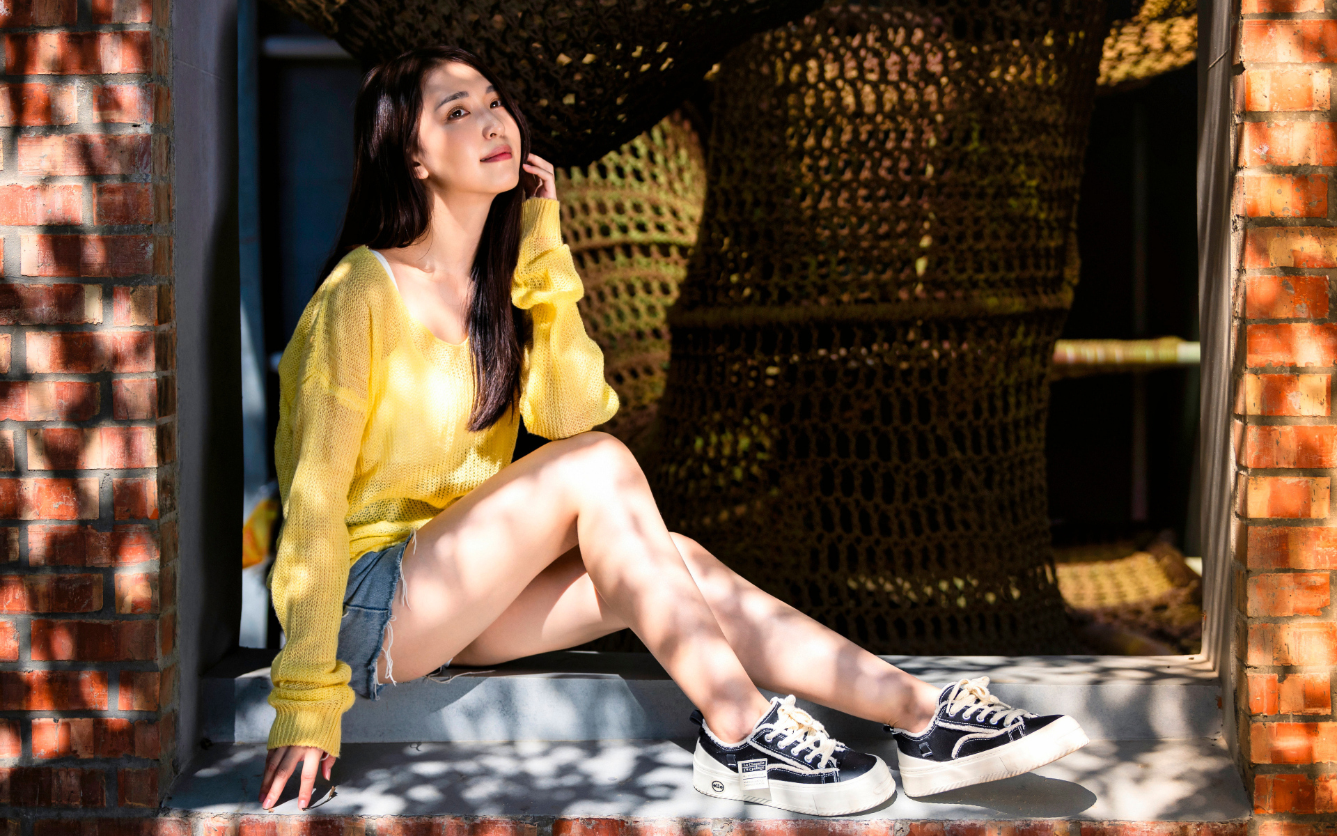 Мечтательная молодая девушка азиатка сидит на окне