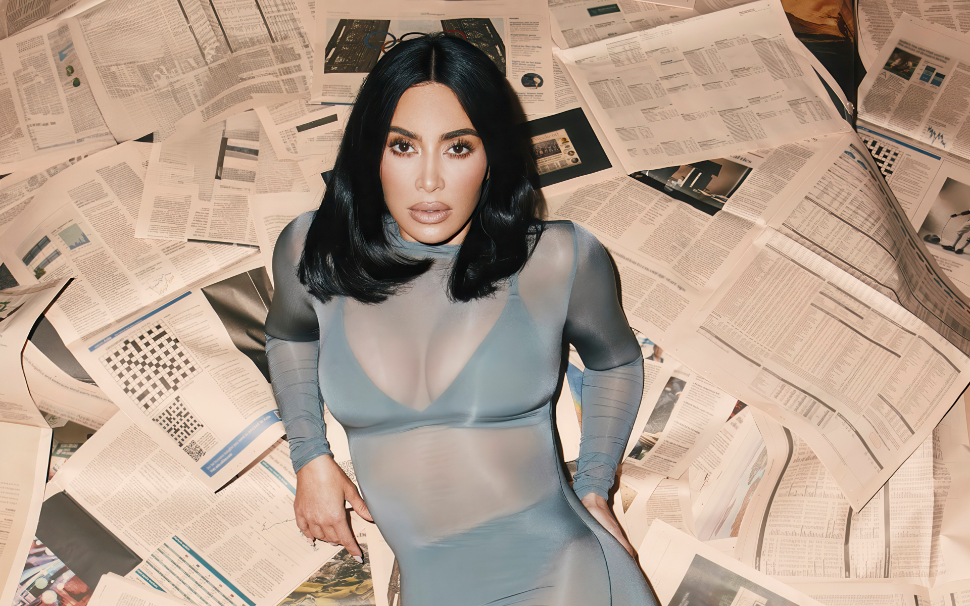 Модель Ким Кардашьян лежит на полу на газетах
