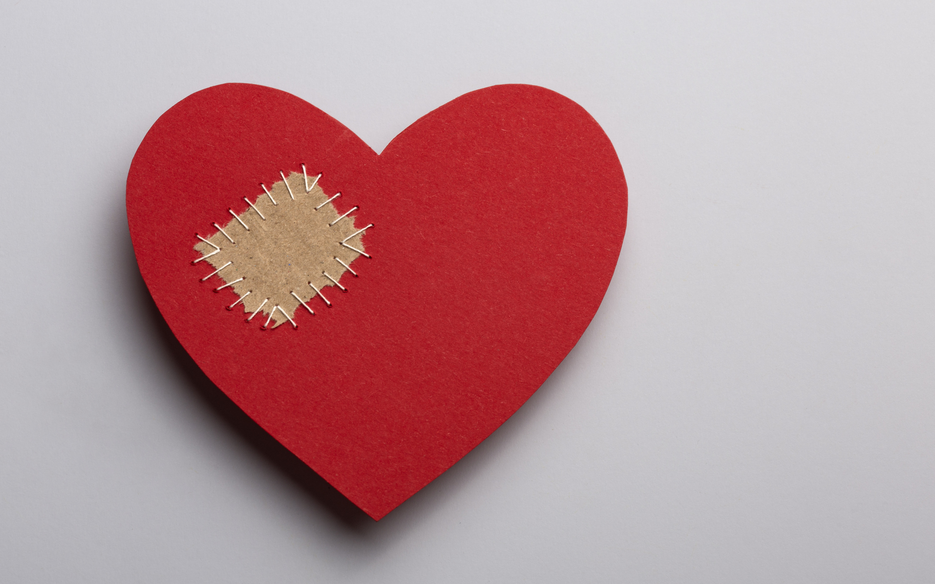 Большое красное сердце с заплаткой на сером фоне