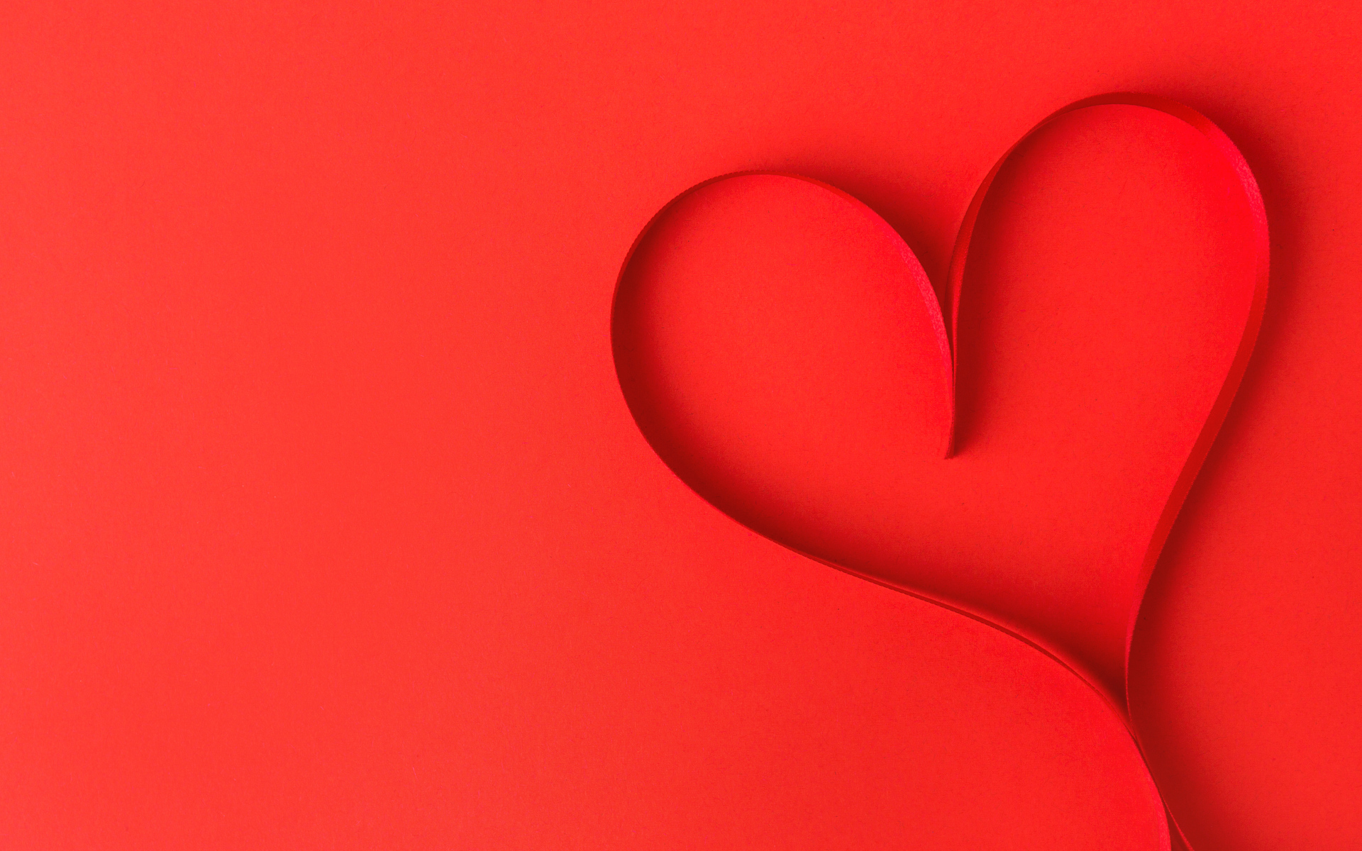 Сердце из атласной ленты на красном фоне