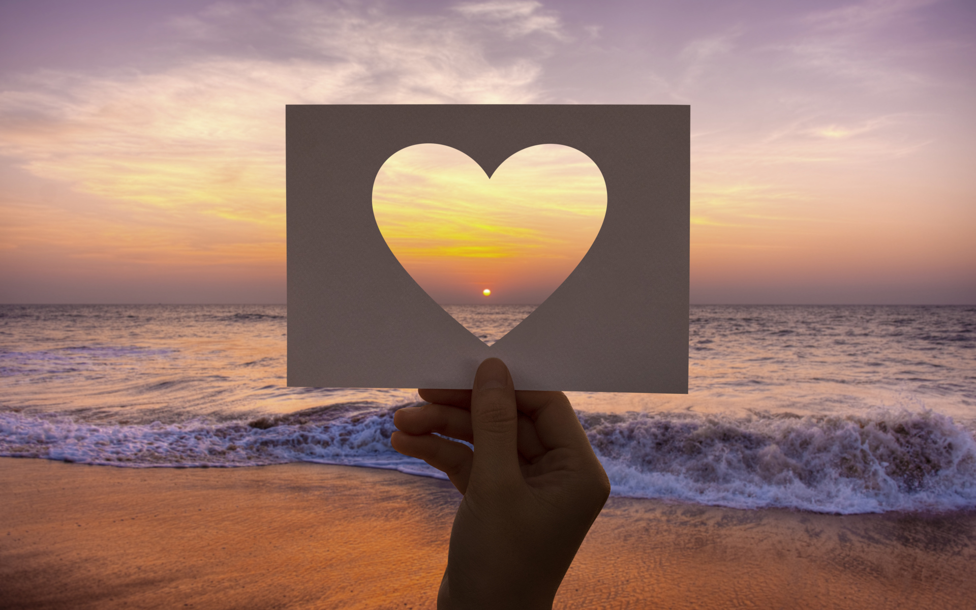 Бумажное сердце на фоне моря на закате солнца