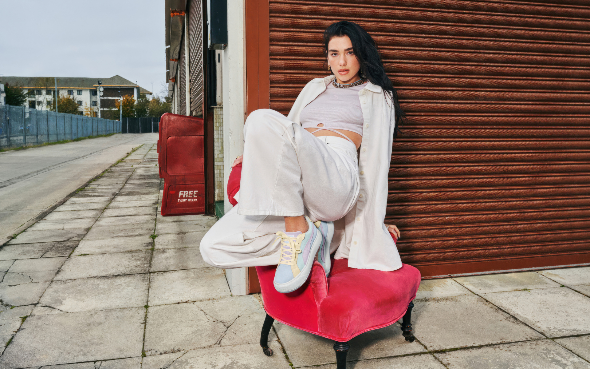 Певица Дуа Липа в белом костюме на кресле у стены