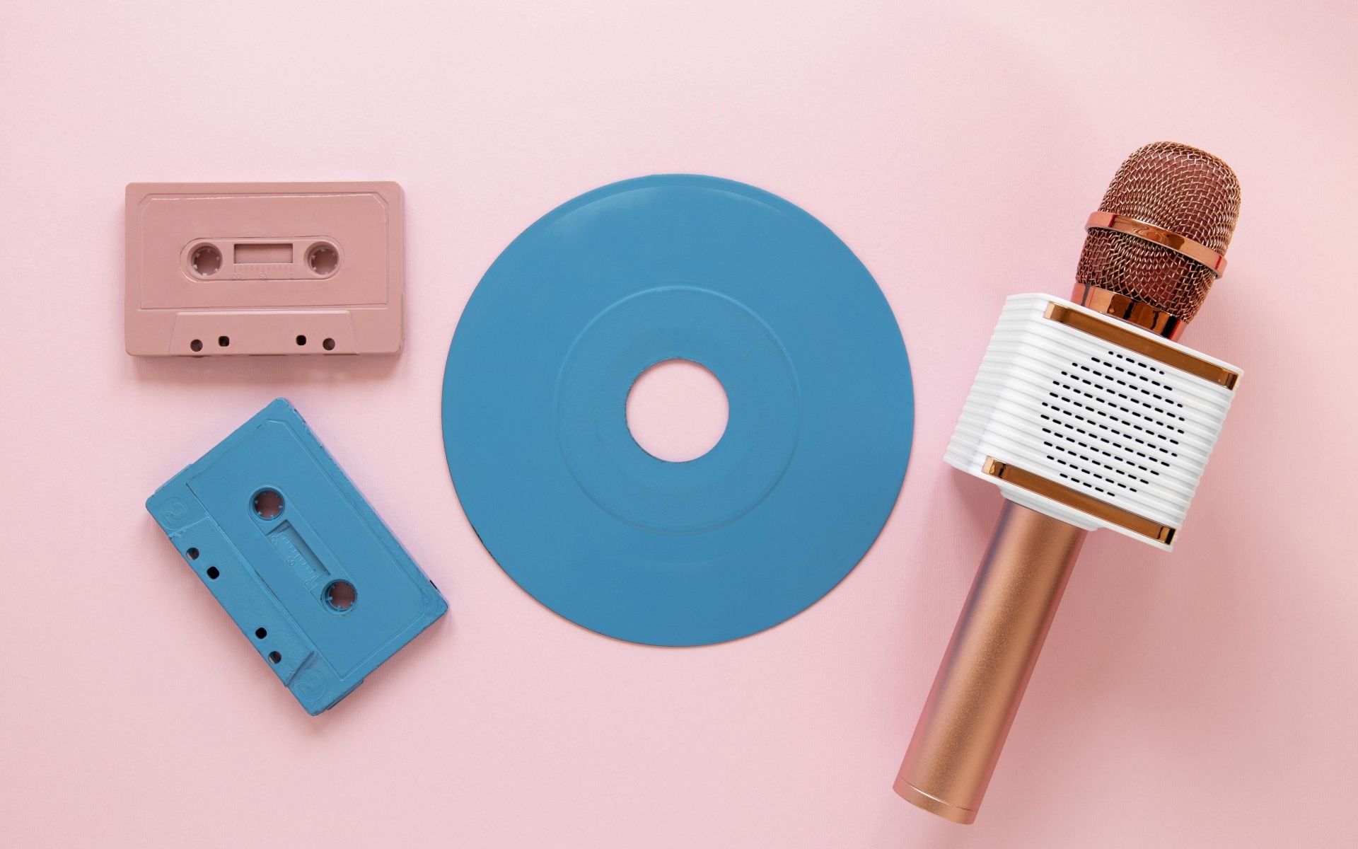Две кассеты, микрофон и пластинка на розовом фоне