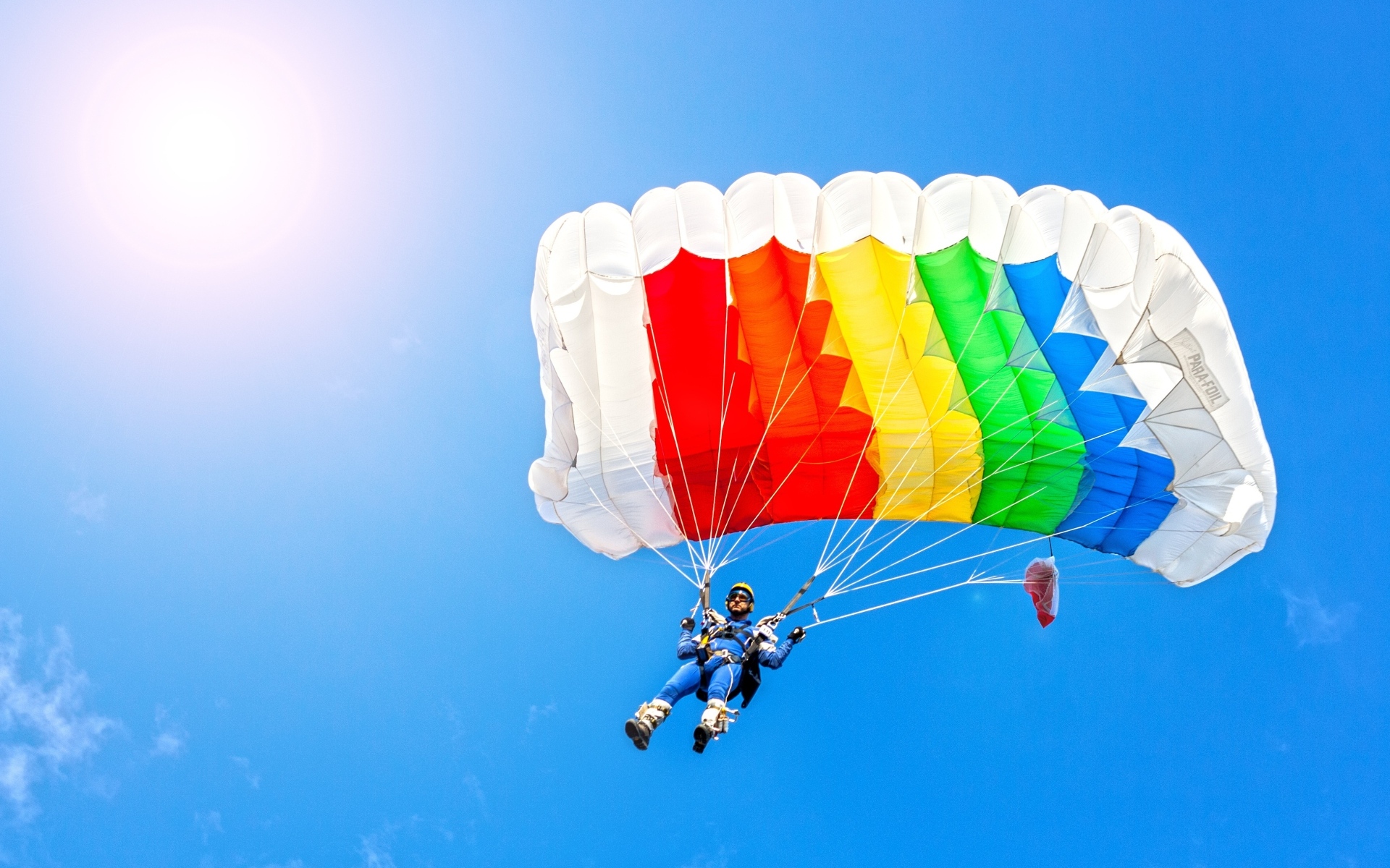 Парашютист в голубом небе в лучах солнца