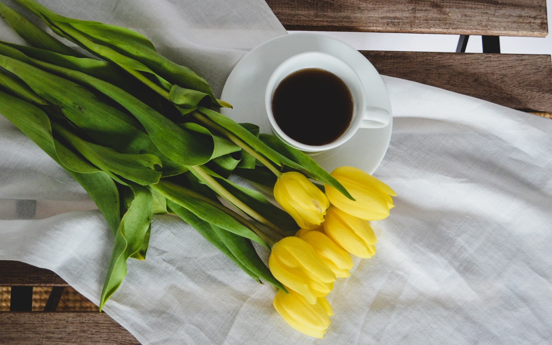 Букет желтых тюльпанов с чашкой кофе на лавке