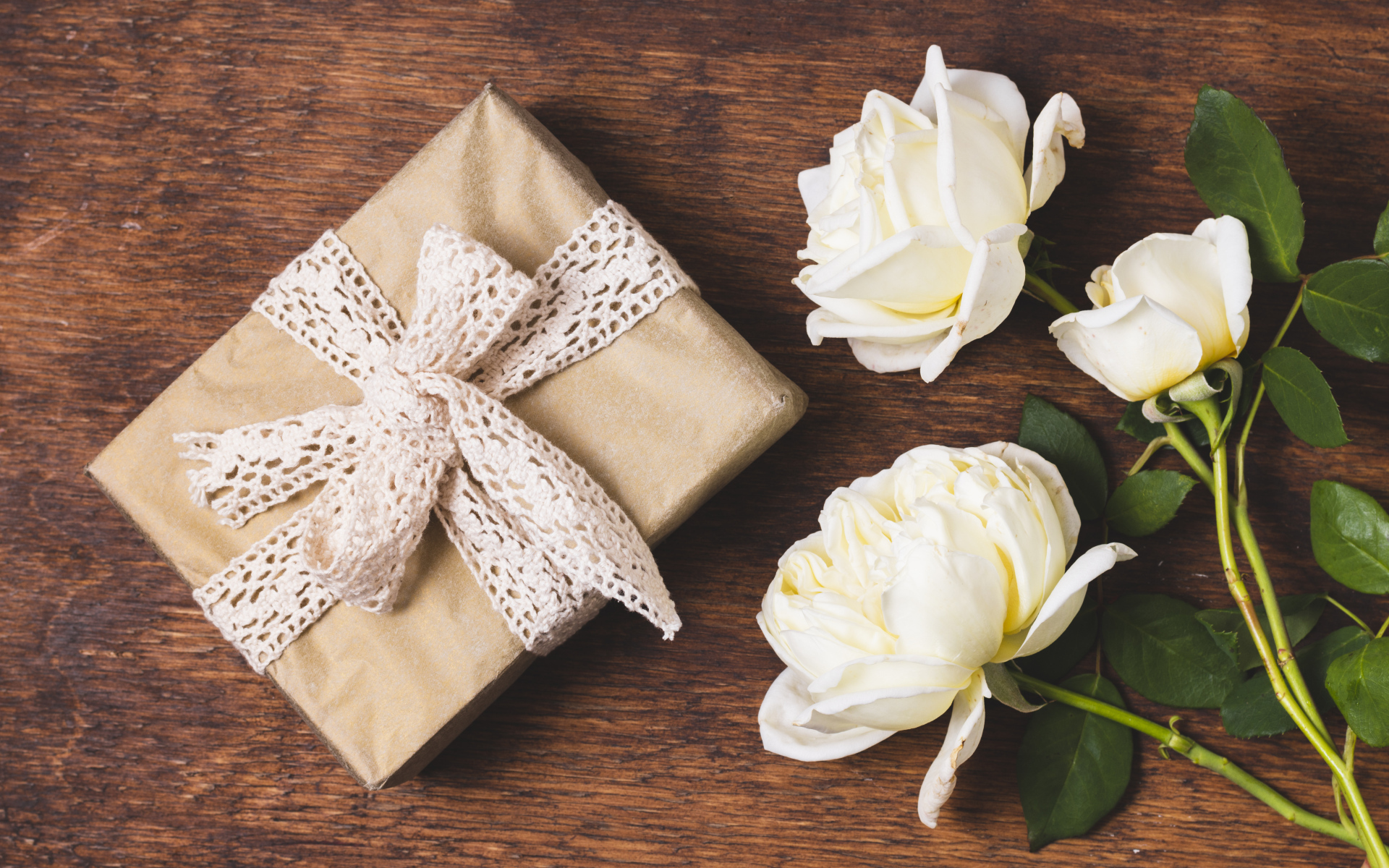 Коробка с подарком на деревянном столе с белыми розами