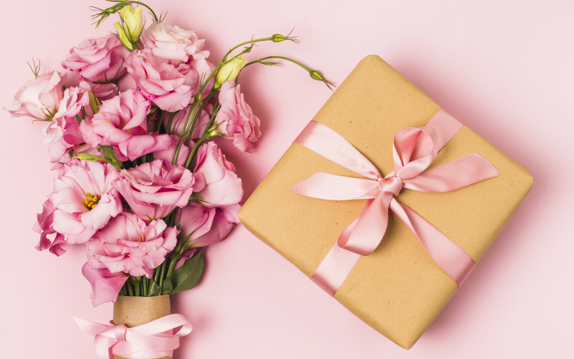 Большой букет эустомы с подарком на розовом фоне