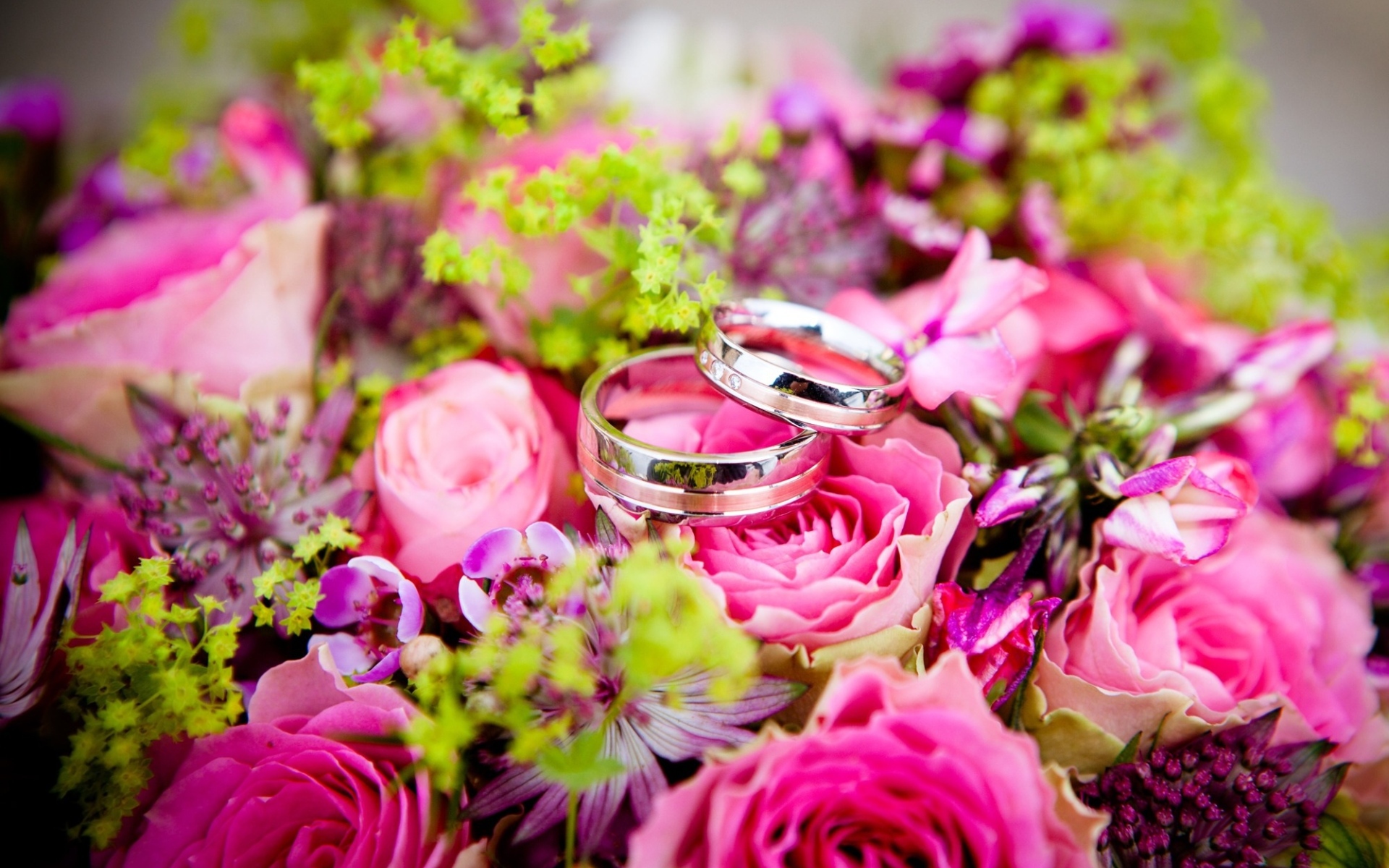 Два обручальных кольцо на букете розовых цветов