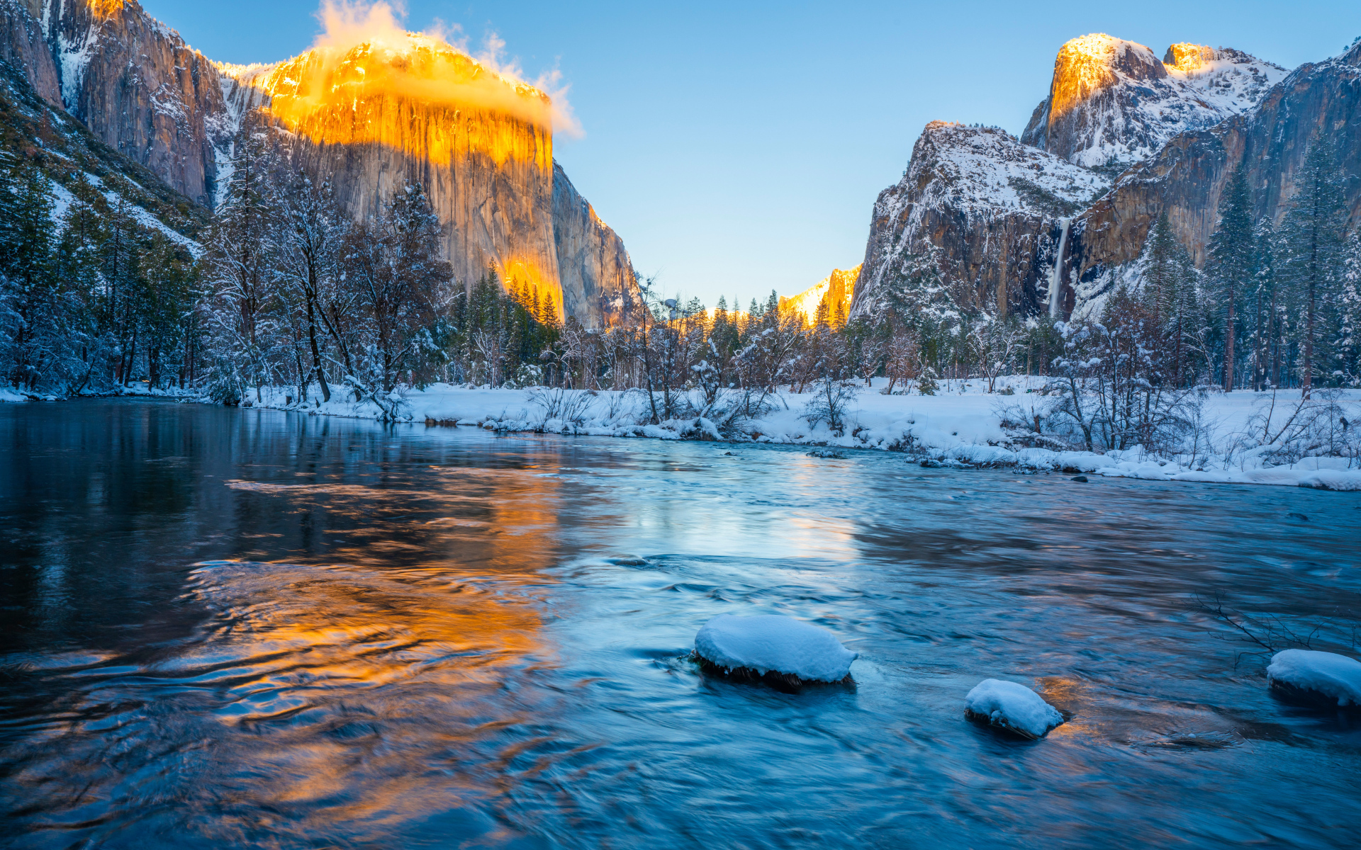 Холодная река с заснеженными берегами и горы в лучах солнца