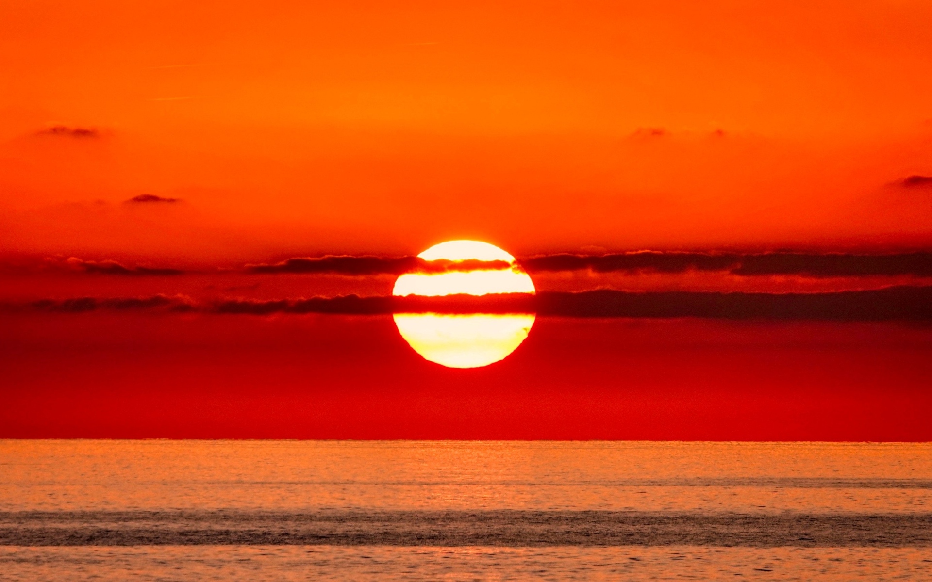 Яркое солнце в облаках на закате над морем 