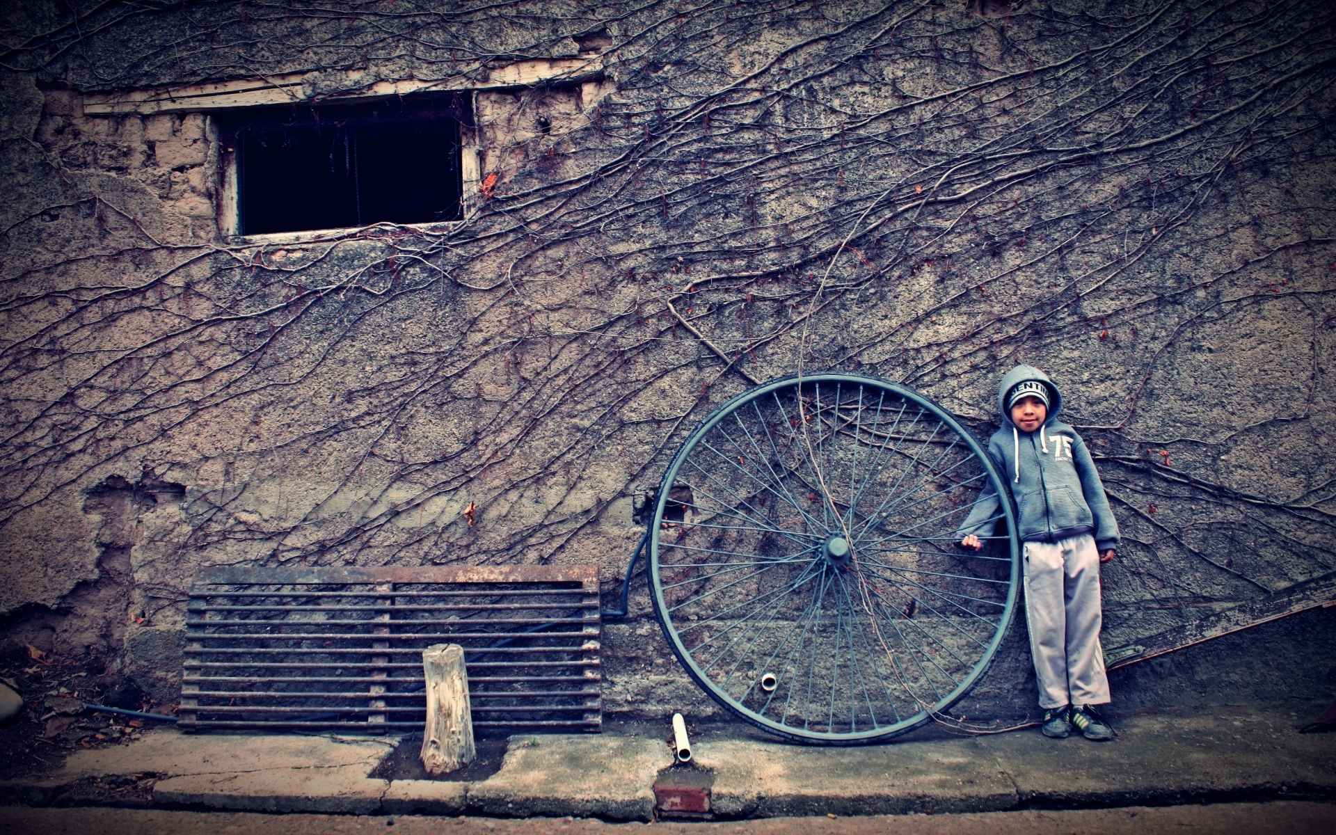 Мальчик с большим колесом стоит у стены