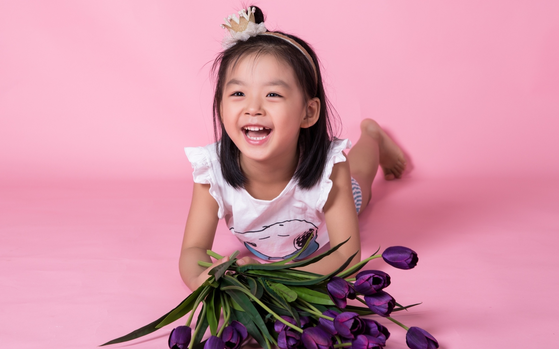 Девочка азиатка в букетом тюльпанов на розовом фоне