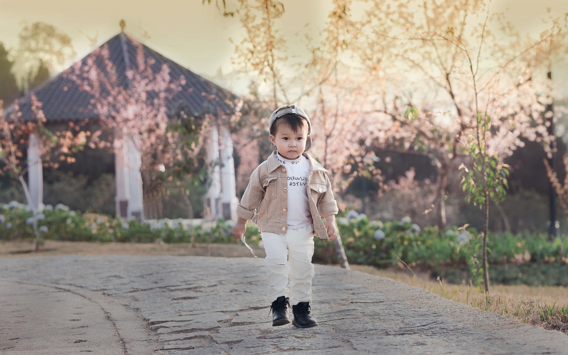 Милый мальчик гуляет по дороге у дома