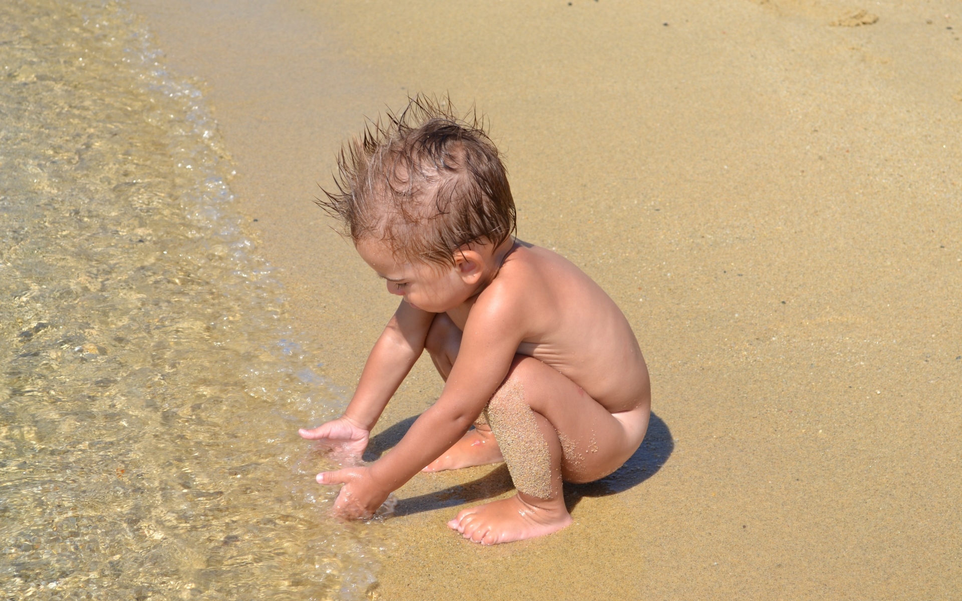 Маленький мальчик на пляже у моря на песке