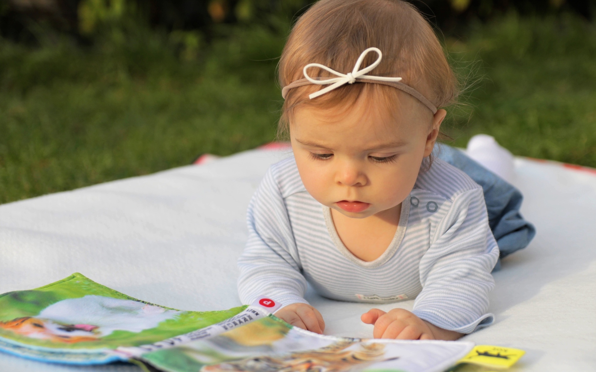 Маленькая девочка с книгой на белом покрывале