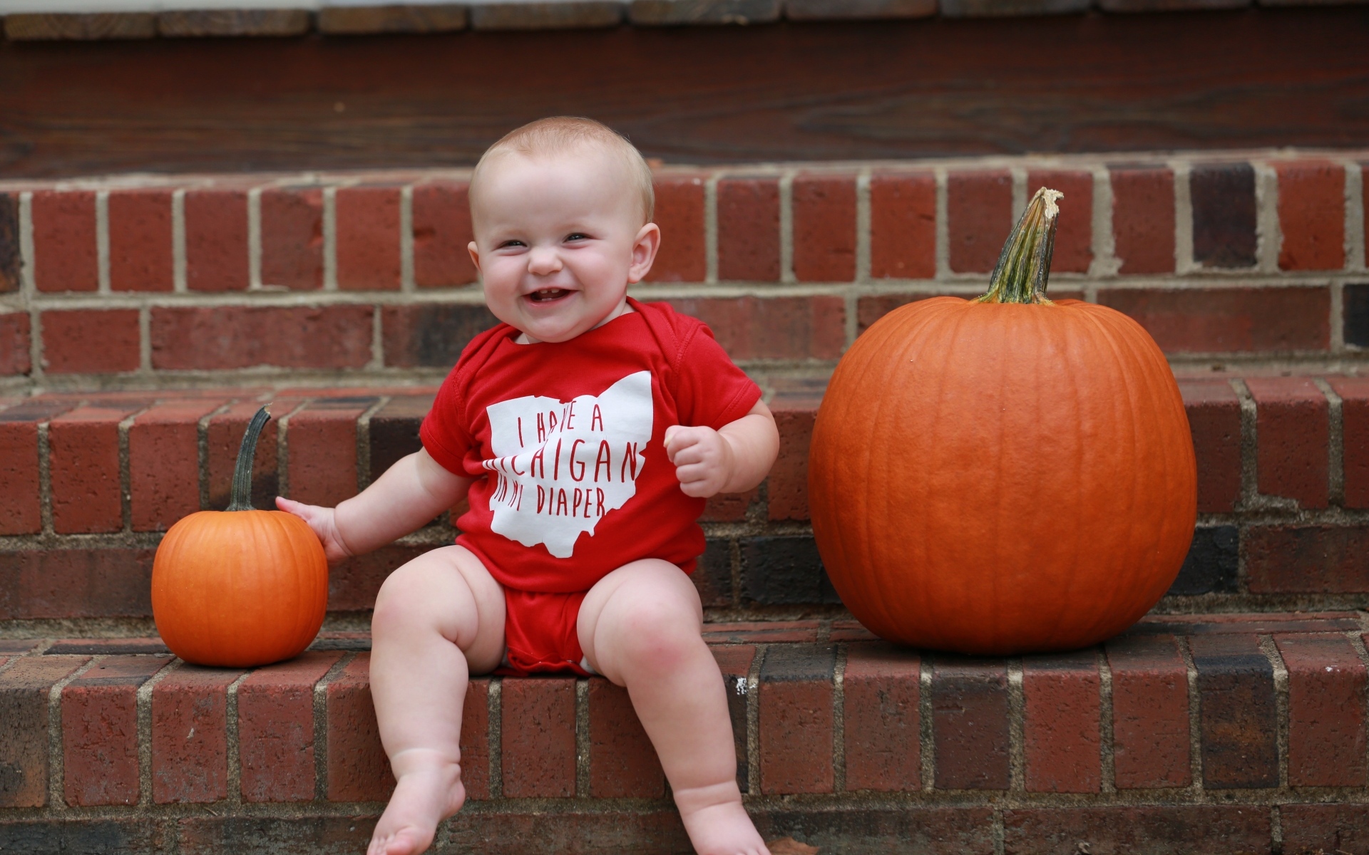 Маленький улыбающийся ребенок с тыквами на ступенях