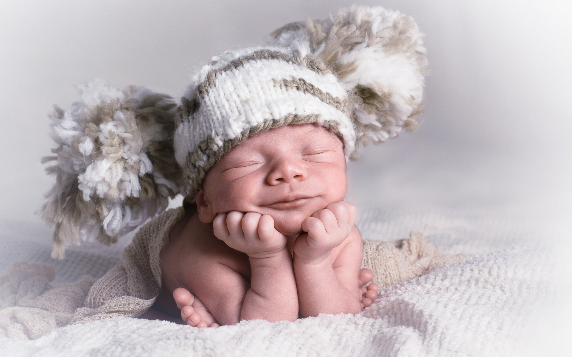 Новорожденный младенец в большой вязаной шапке