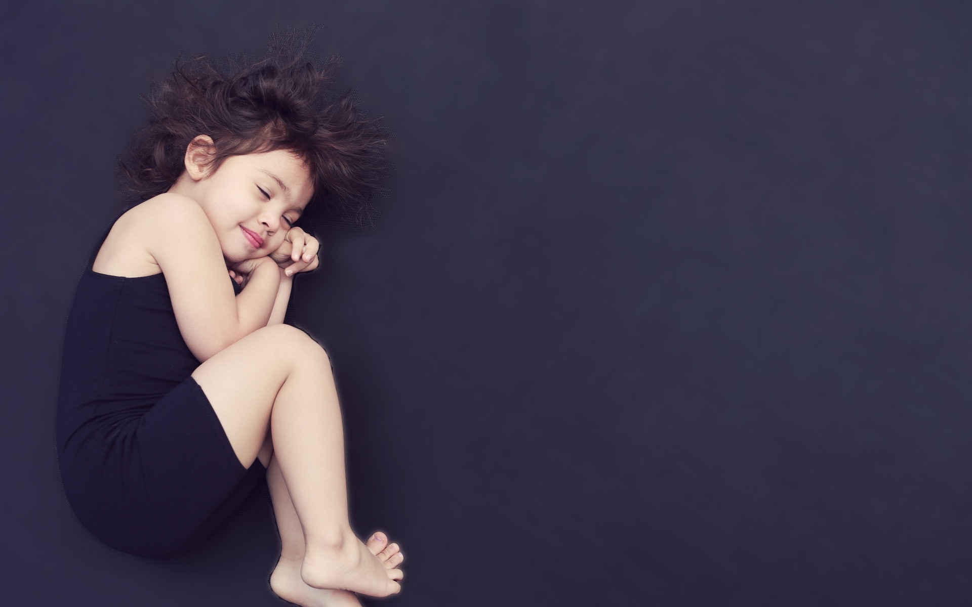Спящая маленькая девочка на сером фоне