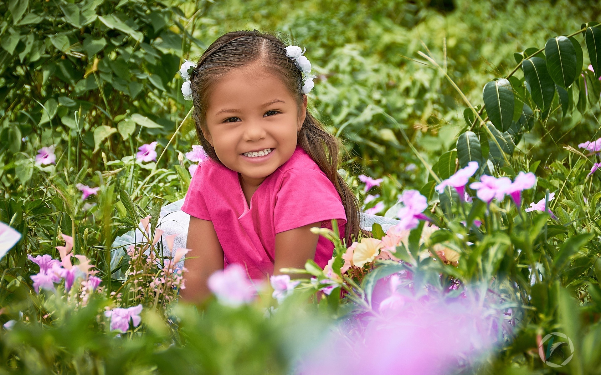 Улыбающаяся маленькая девочка сидит в цветах