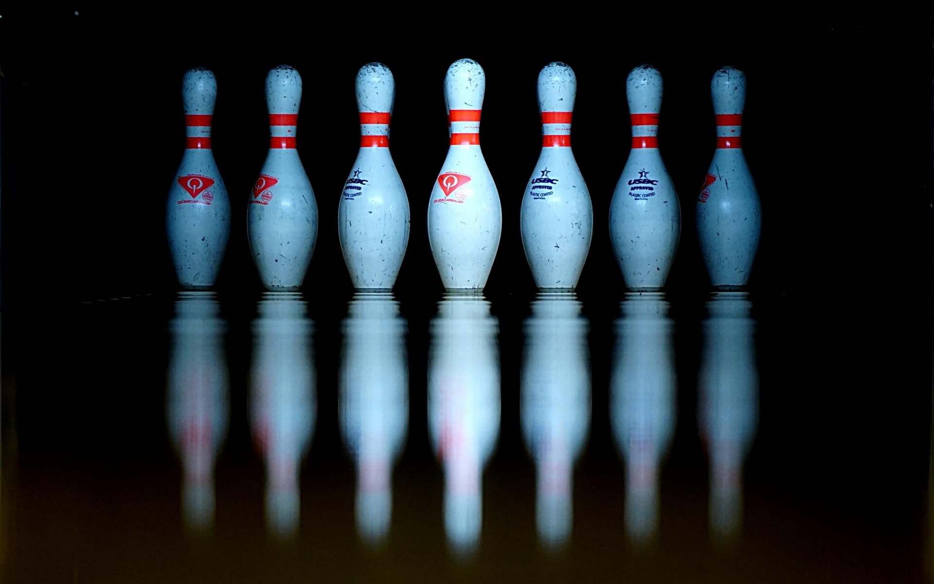 Кегли для боулинга отражаются в черной поверхности 